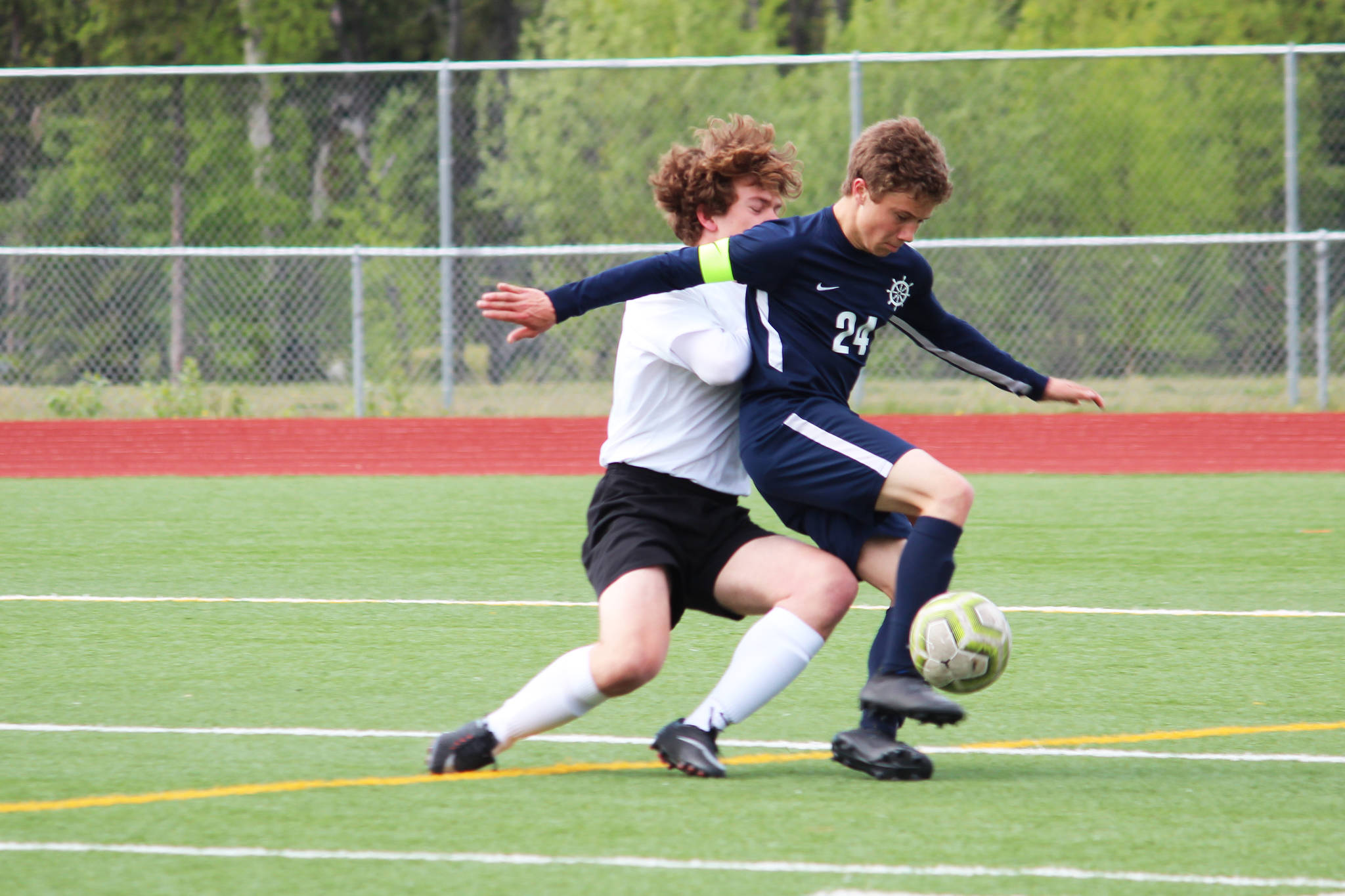 Homer’s Austin Shafford battles to control the ball while under pressure from Grace Christian’s Jackson Tanner during a Friday, May 24, 2019 game in the Division II state soccer championship tournament at Eagle River High School in Eagle River, Alaska. (Photo by Megan Pacer/Homer News)