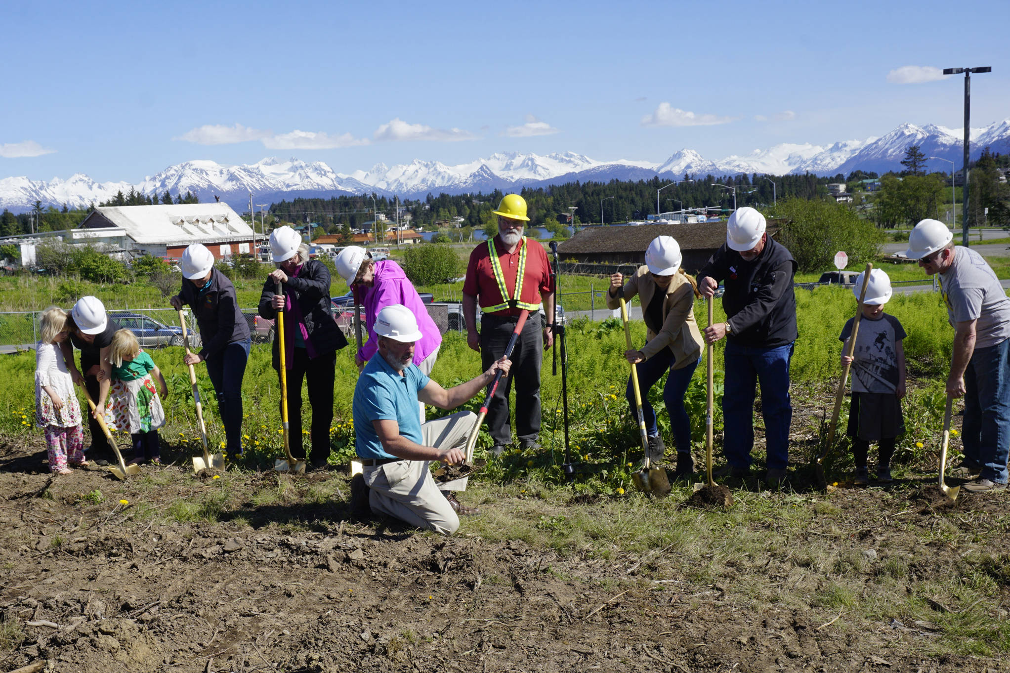 Former Homer Mayor Bryan Zak, in front, shovels dirt at the groundbreaking ceremony for the new Homer Police Station on Grubstake Avenue last Friday, May 24, 2019, in Homer, Alaska. From left to right are Homer City Council member Rachel Lord with her two children, Sadie and Linnea, council member Donna Aderhold, council member Shelly Erickson, council member Caroline Venuti, Mayor Ken Castner, Homer City Manager Katie Koester, and Byron Smith, son of council member Heath Smith, far right. (Photo by Michael Armstrong/Homer News)