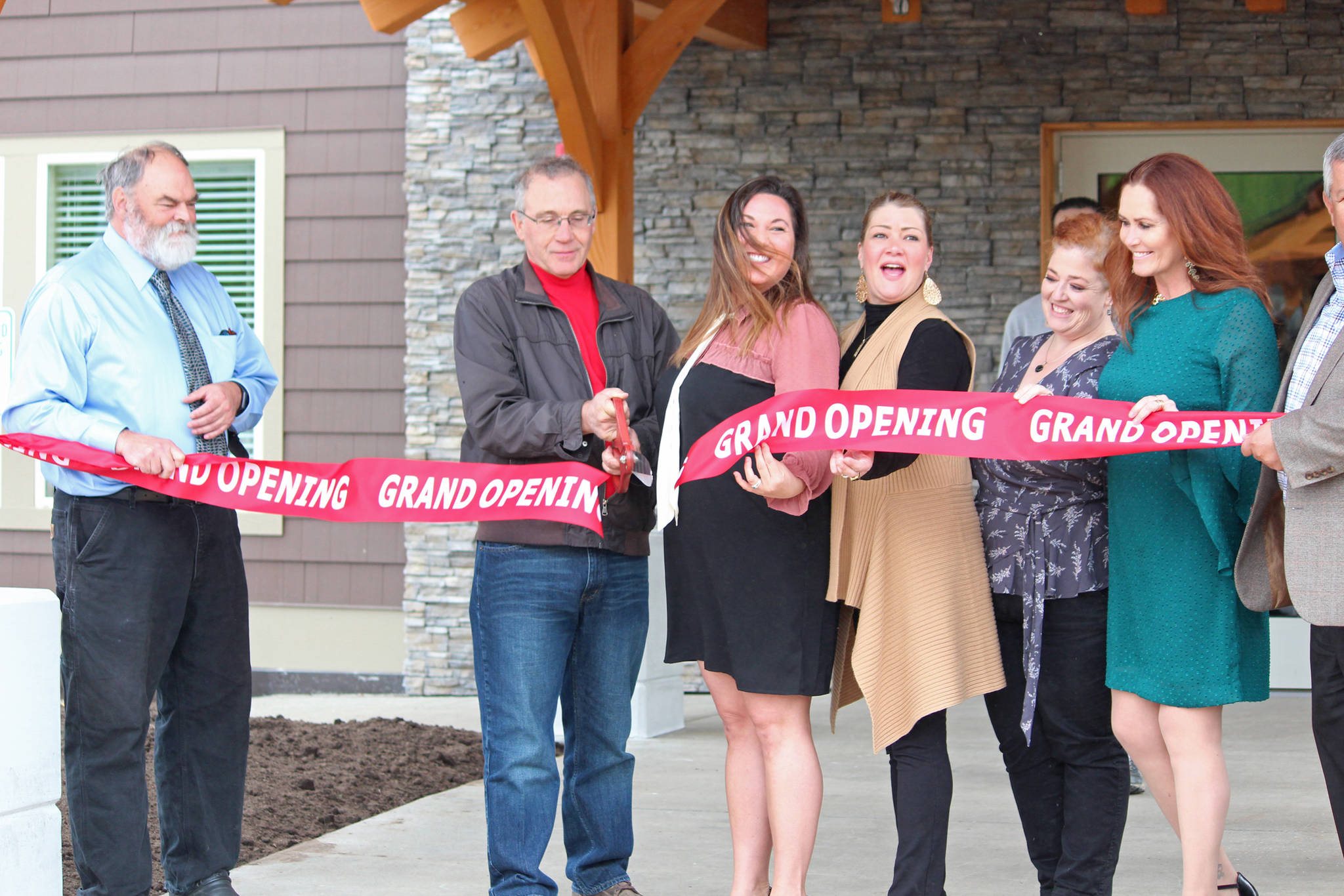 Aspen Hotel chain Owner George Swift cuts a ribbon officially opening the most recent building in Homer, Alaska, during a grand opening ceremony on May 29, 2019. (Photo by Megan Pacer/Homer News)