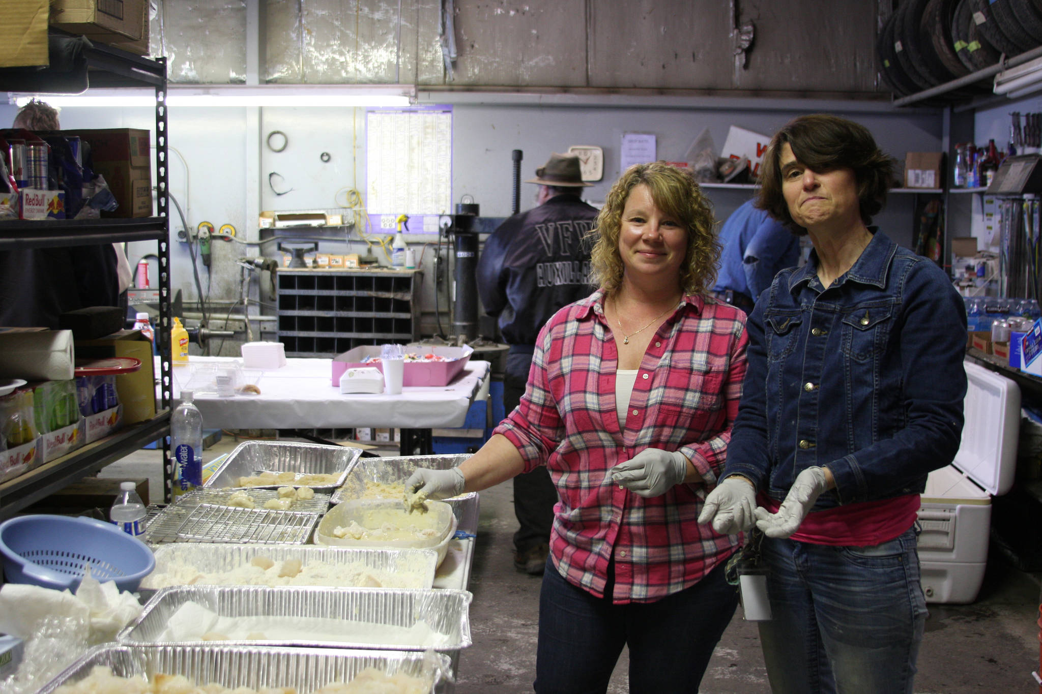 Brandi Blauvelt, left, and Ruth Mitchell, right, prepare freshly caught halibut for the fifth annual Customer Appreciation Day and 50th anniversary celebration on Saturday, May 25 at Thurmond’s Far West Auto in Anchor Point, Alaska. (Photo by Delcenia Cosman)