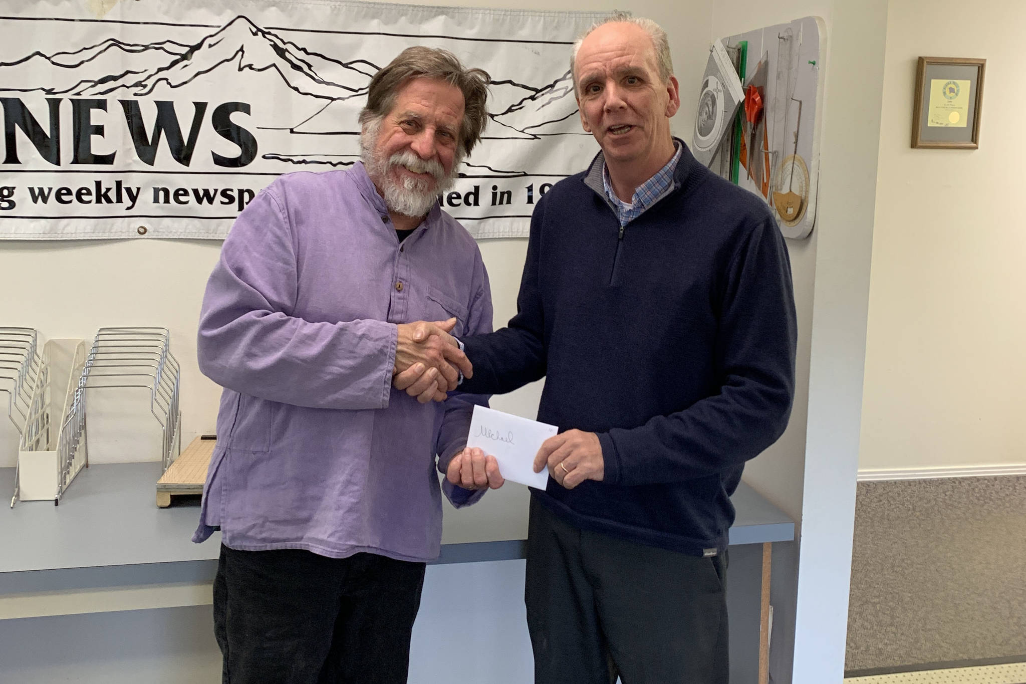 Homer News Editor Michael Armstrong, left, is presented with an award from Publisher Jeff Hayden on May 10, 2019 at the Homer News office in Homer, Alaska. (Photo by Malia Anderson)