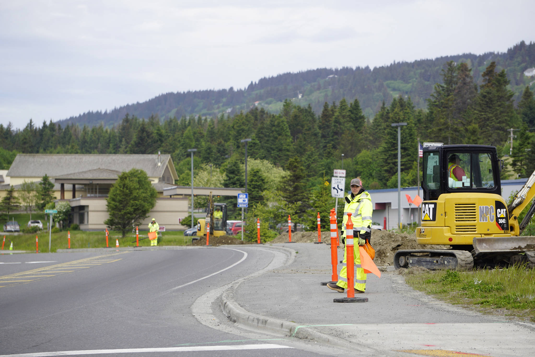 Flaggers direct traffic while workers install a fiber-optic line on the Homer Bypass to connect the Lake Street intersection traffic light with a new traffic light to be built at Main Street and the Homer Bypass on June 4, 2019 in Homer, Alaska (Photo by Michael Armstrong/Homer News)
