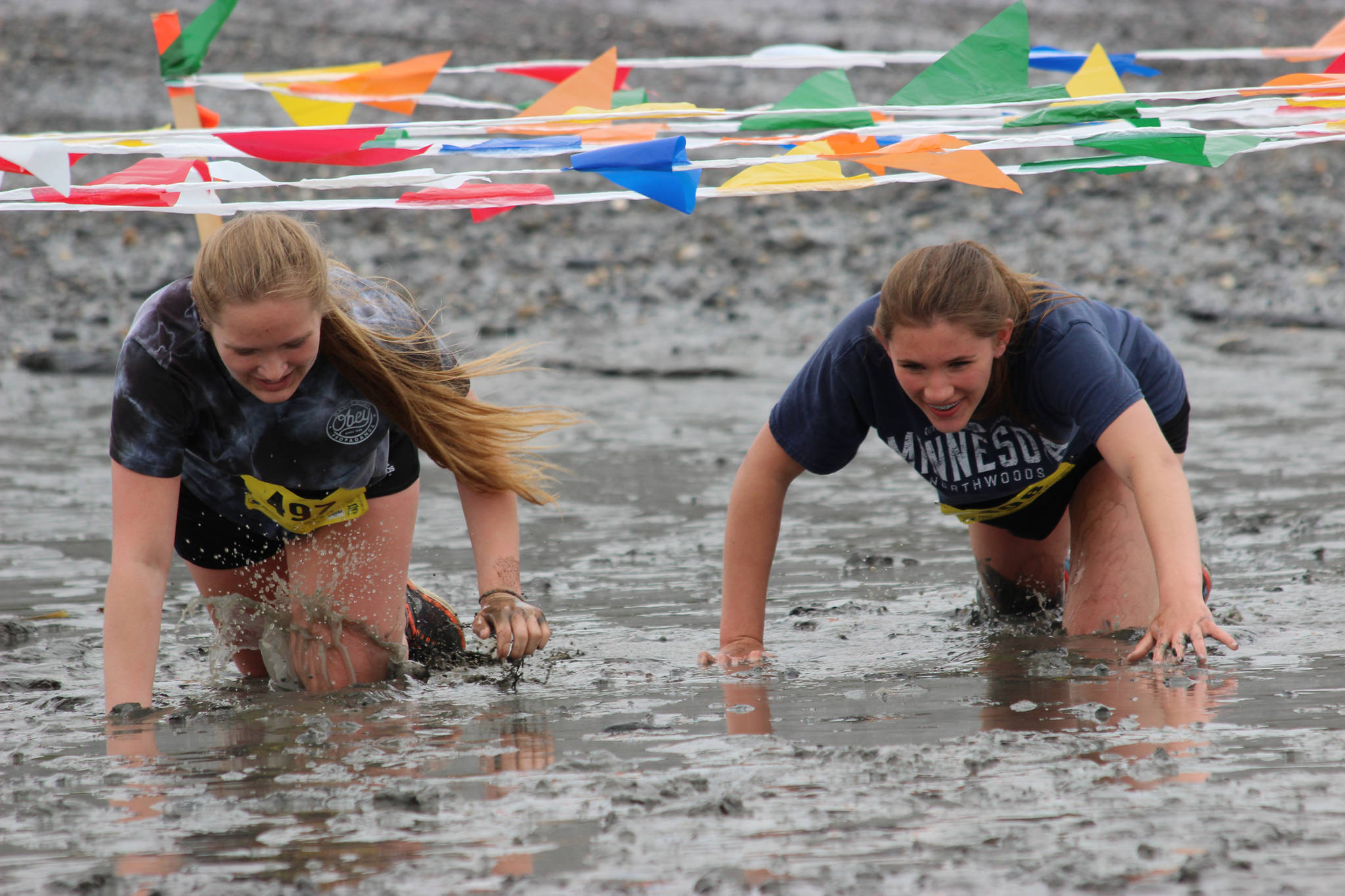 The mother-and-daughter team Kaylee Fenn, left, and Julia Hanson, right, navigate through one of the course challenges in the 2018 5K Clam Scramble, held June 16, 2018, in Ninilchik, Alaska. The fun run is held during low tide on Ninilchik beach. (Photo by Sabrina Ferguson)