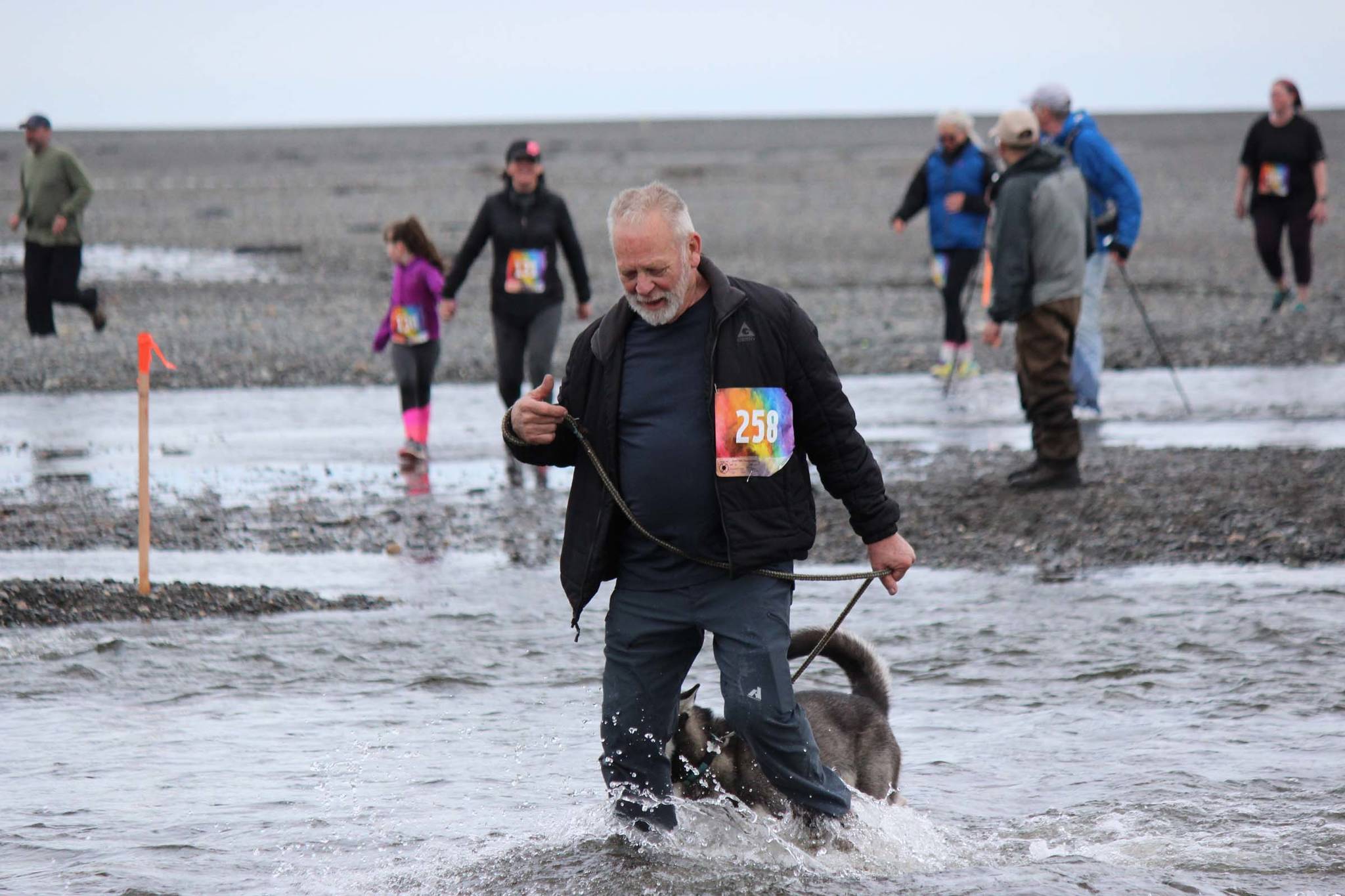 Tom Farrell and his canine running partner, Kiladai, cross the mouth of Deep Creek. Farrell, 80, was the oldest participate in 2019 Clam Scramble, a 5K fun run held on Saturday, June 15, 2019 in Ninilchik, Alaska. (Photo by McKibben Jackinsky)