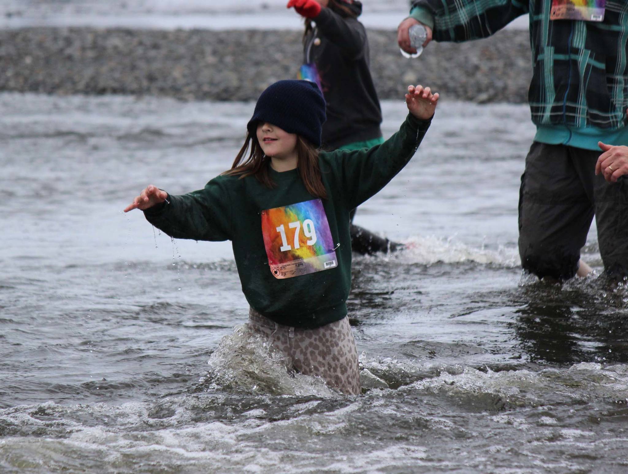 Unbothered by a drooping sweatshirt hood, Emma Berger, 179, relies on her feet to find a way across the gravel bottom of Deep Creek during the Clam Scramble held June 15, 2019 in Ninilchik, Alaska. (Photo by McKibben Jackinsky)
