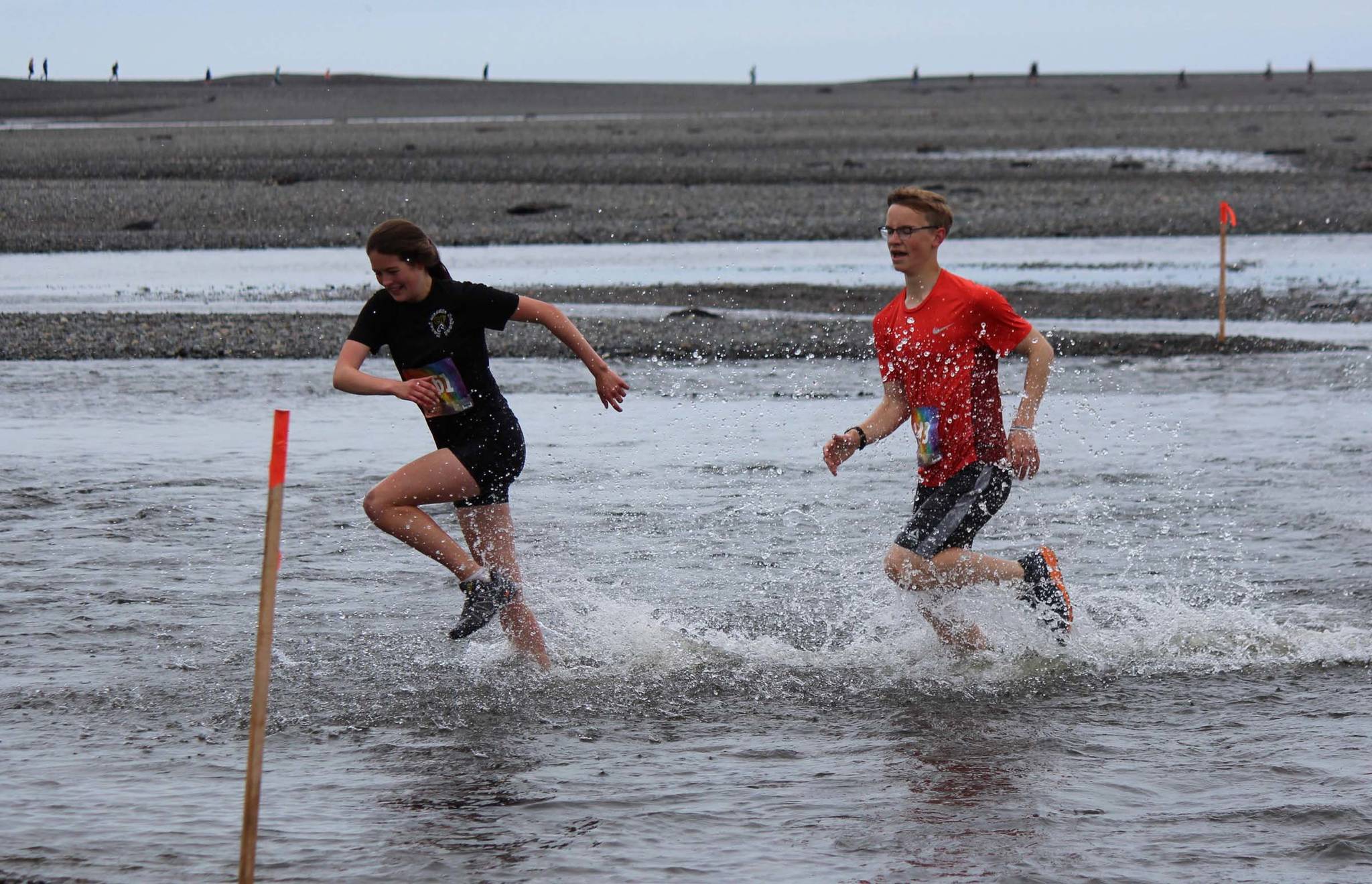 Leah Fallon, left, and Tyler Hippchen, right, dash through the chilly water of Deep Creek in the Clam Scramble, held Saturday, June 15, 2019, in Ninilchik, Alaska. Fallon finished ninth overall and was the first female finisher with a time of 29 minutes, 42 seconds. Hippchen finished seventh overall in 29:36.(Photo by McKibben Jackinsky)