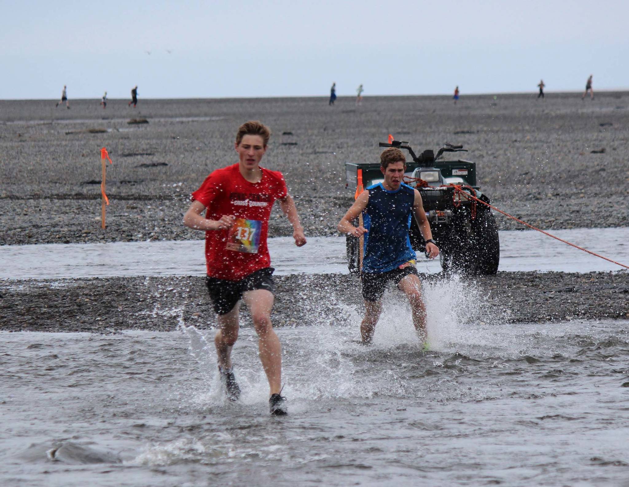 Maison Dunham, fastest finisher in the Clam Scramble of 2017 and 2018, is the first runner to cross the mouth of Deep Creek in the 2019 event, held on Saturday, June 15, 2019, in Ninilchik, Alaska. Close on his heels is Aaron Swedberg, who eventually pulled ahead and finished the 5K event with a time of 22 minutes, 16 seconds. Dunham finished in 22:17. (Photo by McKibben Jackinsky)