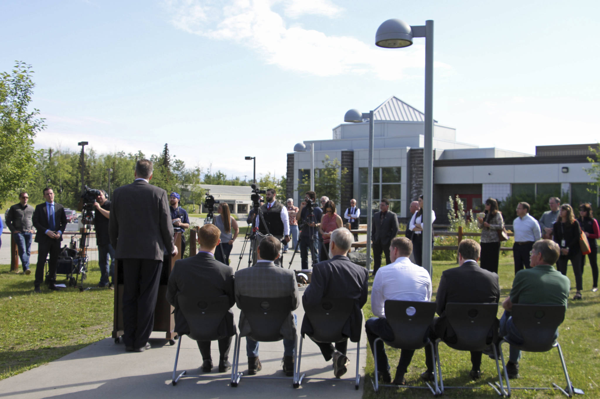Alaska Gov. Mike Dunleavy, standing at podium, speaks at a news conference Friday, June 14, 2019, in Wasilla, Alaska. Dunleavy has called lawmakers into special session July 8 in Wasilla, and his administration gave a tour of the recommended site at Wasilla Middle School to reporters. (AP Photo/Mark Thiessen)