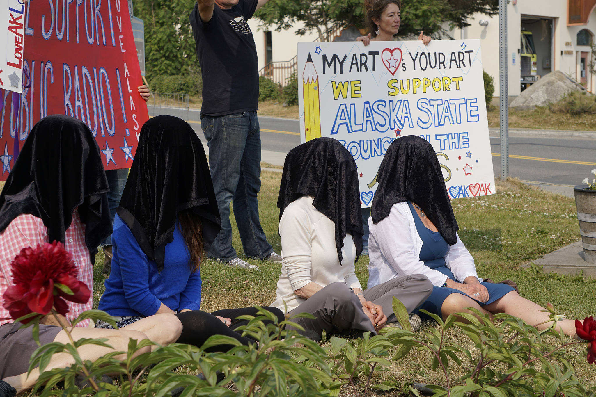 Women draped in black sit down on July 9, 2019, at WKFL Park in Homer, Alaska, as part of a statewide art intervention to protest Gov. Mike Dunleavy’s veto of a $2.8 million state appropriation to the Alaska State Council on the Arts. They also supported a general override of Dunleavy’s vetoes that will affect funding for the University of Alaska, public radio and other programs. (Photo by Michael Armstrong/Homer News)
