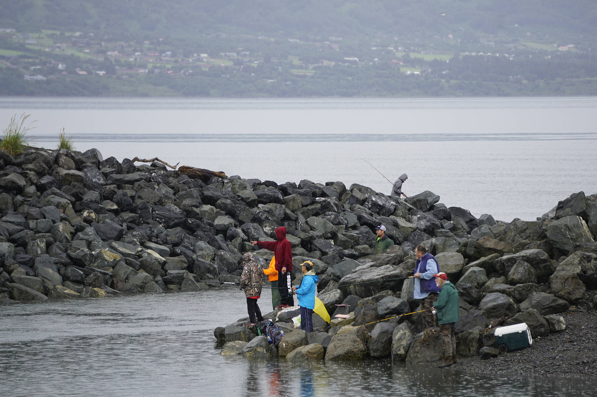 Anglers fish on July 15, 2019, at the mouth of the Nick Dudiak Fishing Lagoon in Homer, Alaska. Rain fell over the weekend after a weeks-long stretch of sunny weather. (Photo by Michael Armstrong/Homer News)