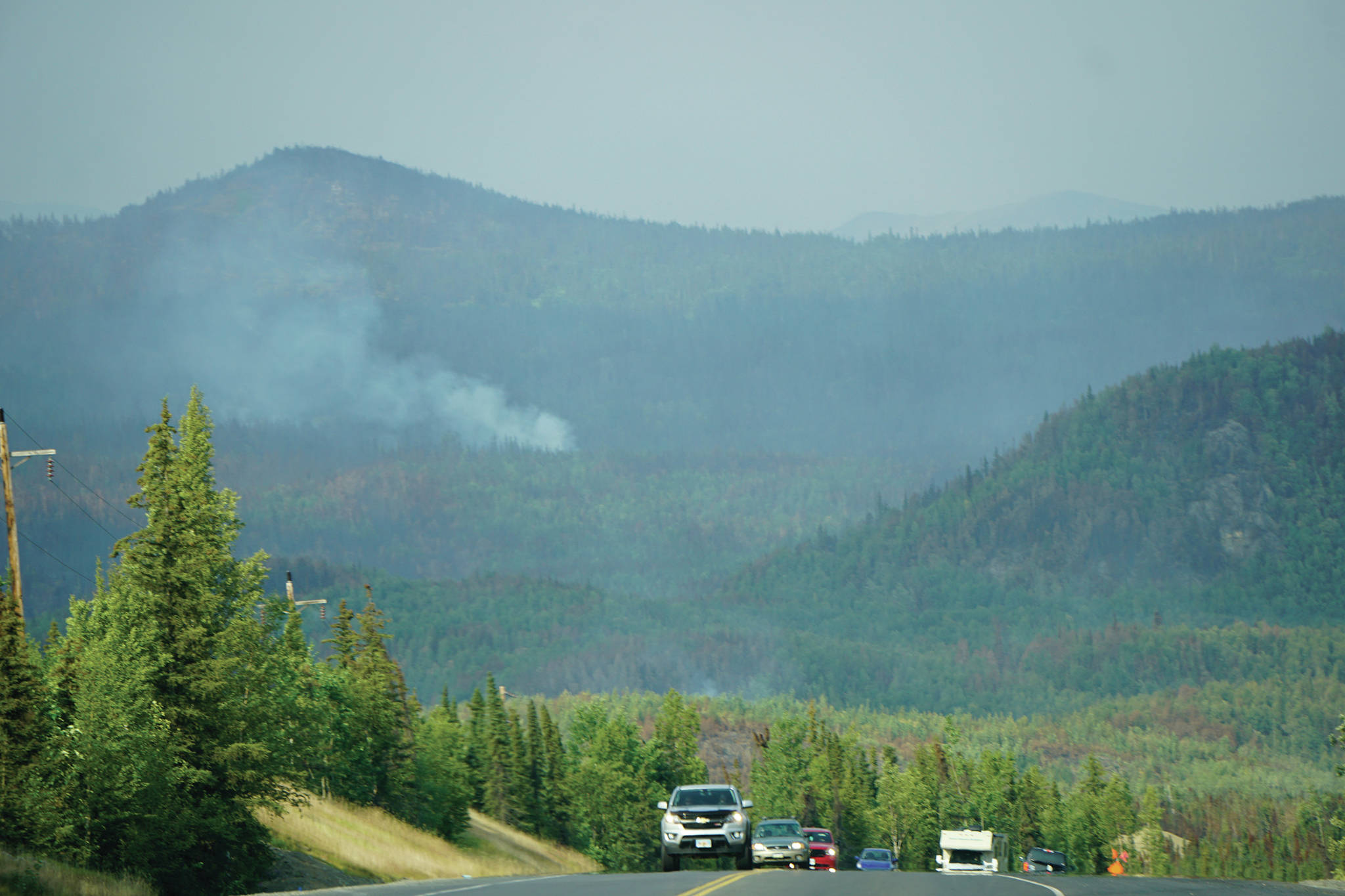 A plume of smoke rises from the Swan Lake fire area as vehicles head south on the Sterling Highway on July 18, 2019, near Skilak Lake, Alaska. (Photo by Michael Armstrong/Homer News)