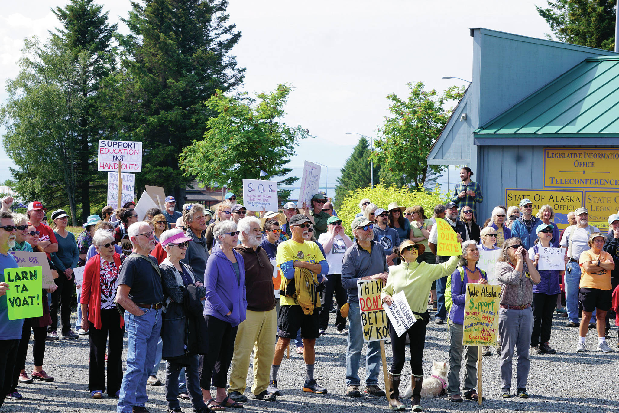 Demonstrators listen to speakers at a rally Sunday, July 28, 2019, against Gov. Mike Dunleavy’s budget cuts at the Legislative Information Office, Homer, Alaska. (Photo by Michael Armstrong/Homer News).