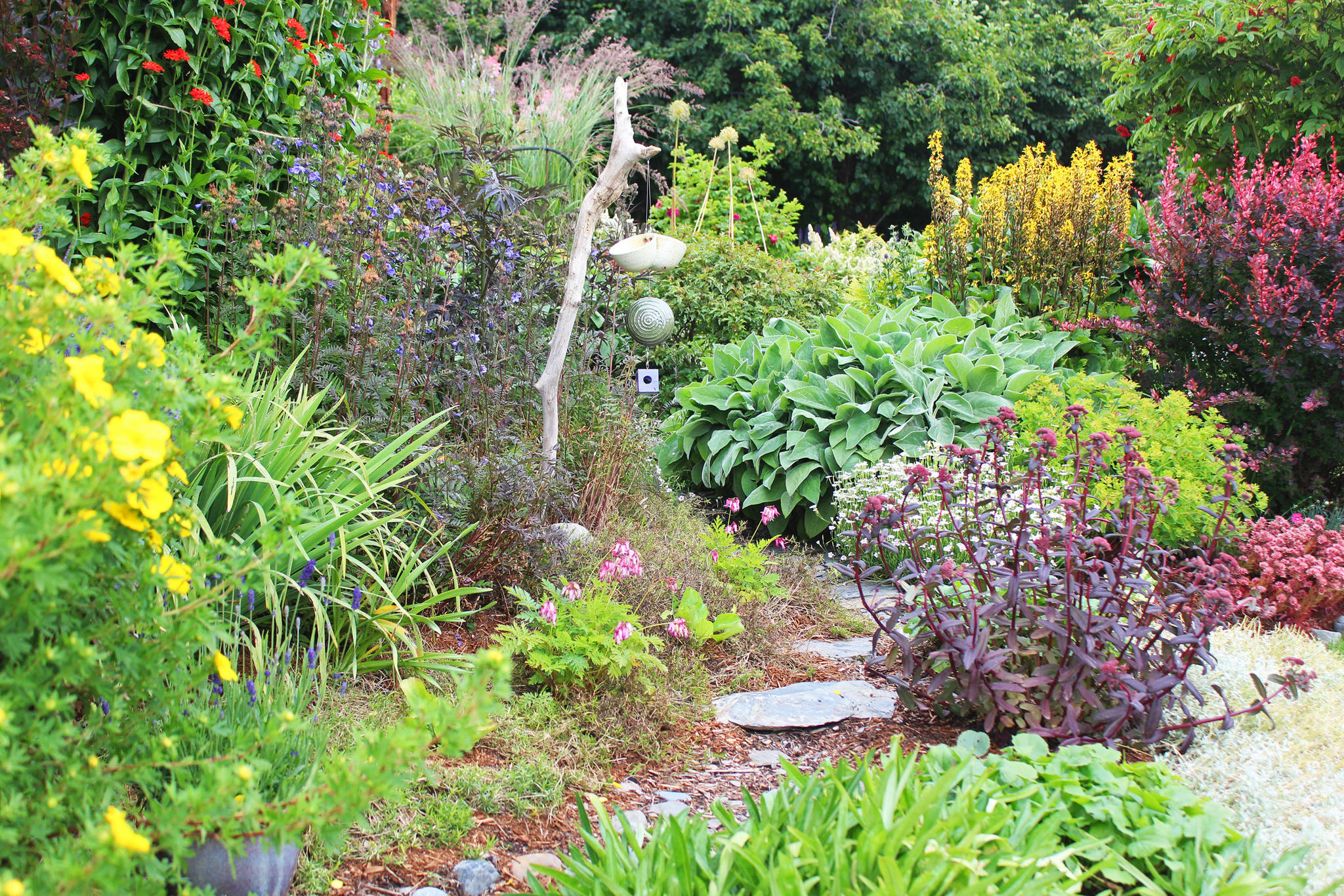A stone walkway winds through one of the five expansive gardens available for visiting through the annual Garden Tour, held this year on Sunday, July 28, 2019 in and around Homer, Alaska. (Photo by Megan Pacer/Homer News)