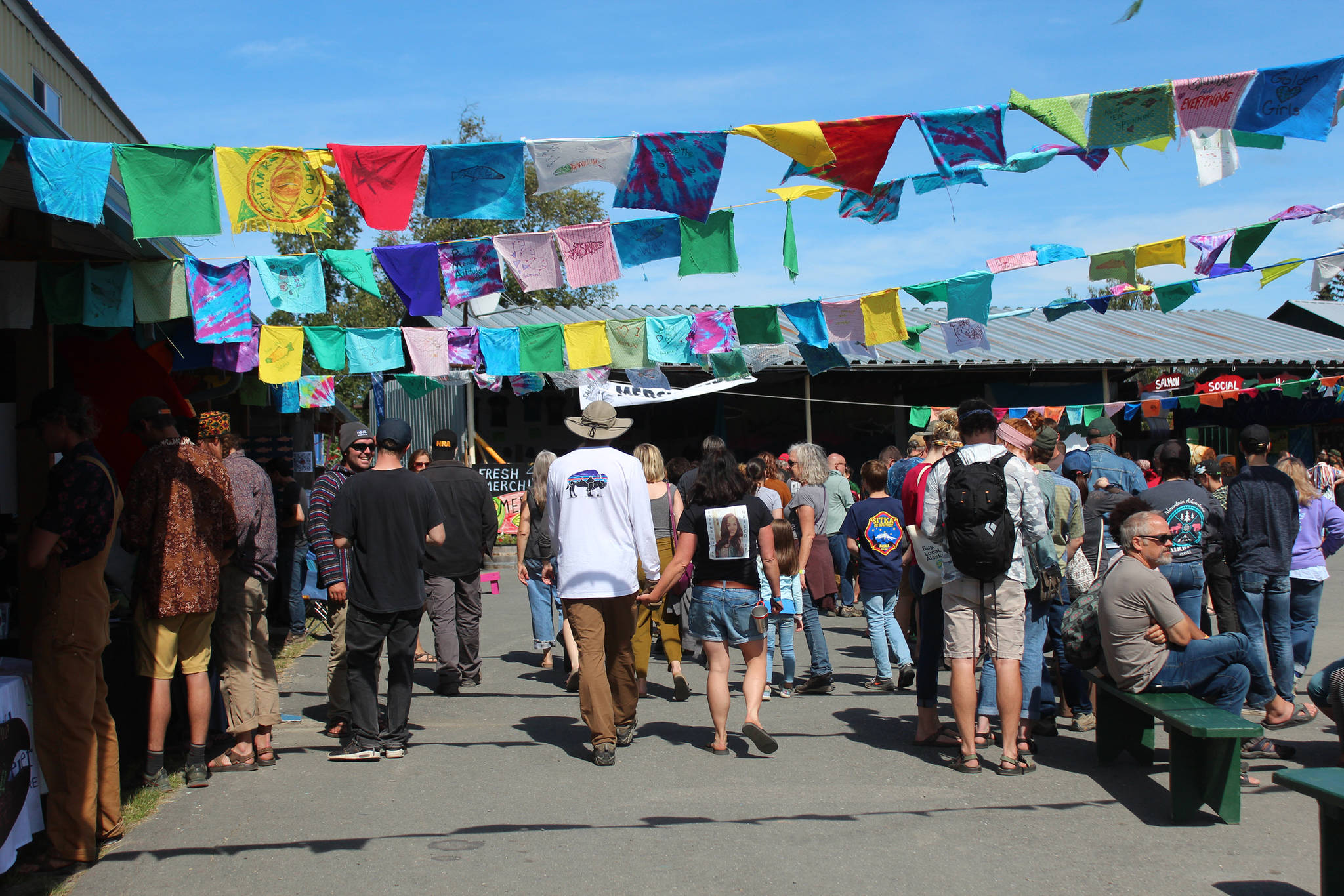 Festival goers walk through the Salmon Causeway — the collection of education and advocacy booths — on Friday, Aug. 2, 2019 at Salmonfest in Ninilchik, Alaska. (Photo by Megan Pacer/Homer News)