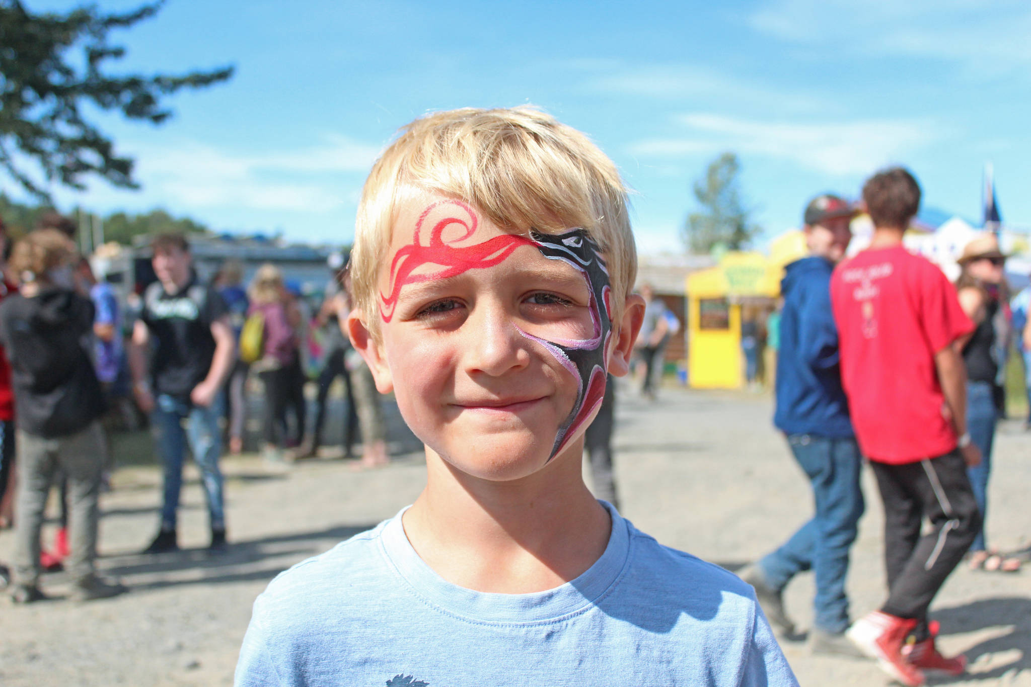 Iver Ledahl, 8, of Kenai, shows off the finished product of his face paint on Friday, Aug. 2, 2019 at Salmonfest in Ninilchik, Alaska. (Photo by Megan Pacer/Homer News)