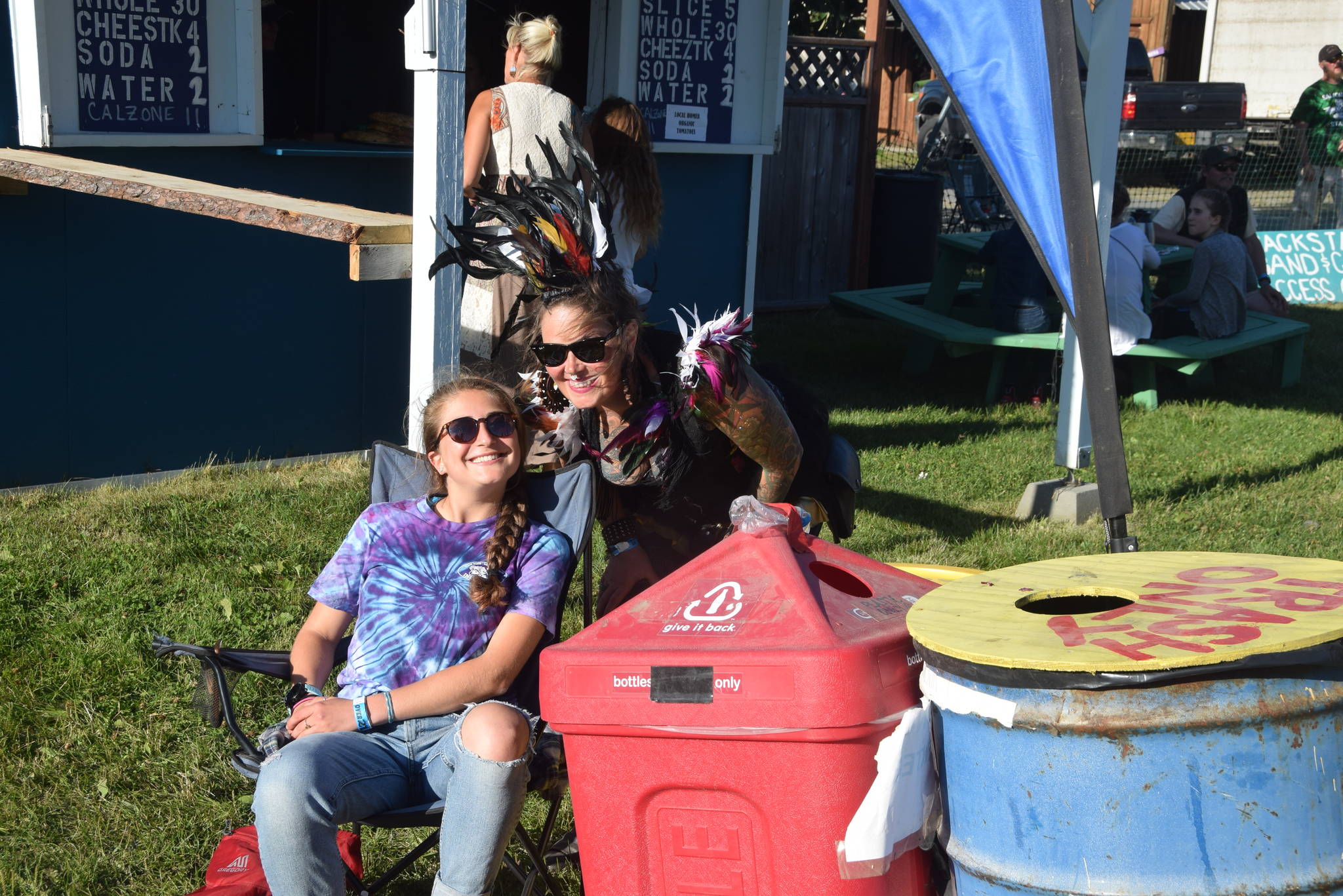 Photo by Brian Mazurek/Peninsula Clarion                                 Rosie Skovron, left, and a Salmonfest attendee smile for the camera at one of the waste disposal stations during Salmonfest 2019 in Ninilchik, Alaska on August 2, 2019. Skovron is a volunteer for the Zero Waste project and an intern at Cook Inletkeeper.