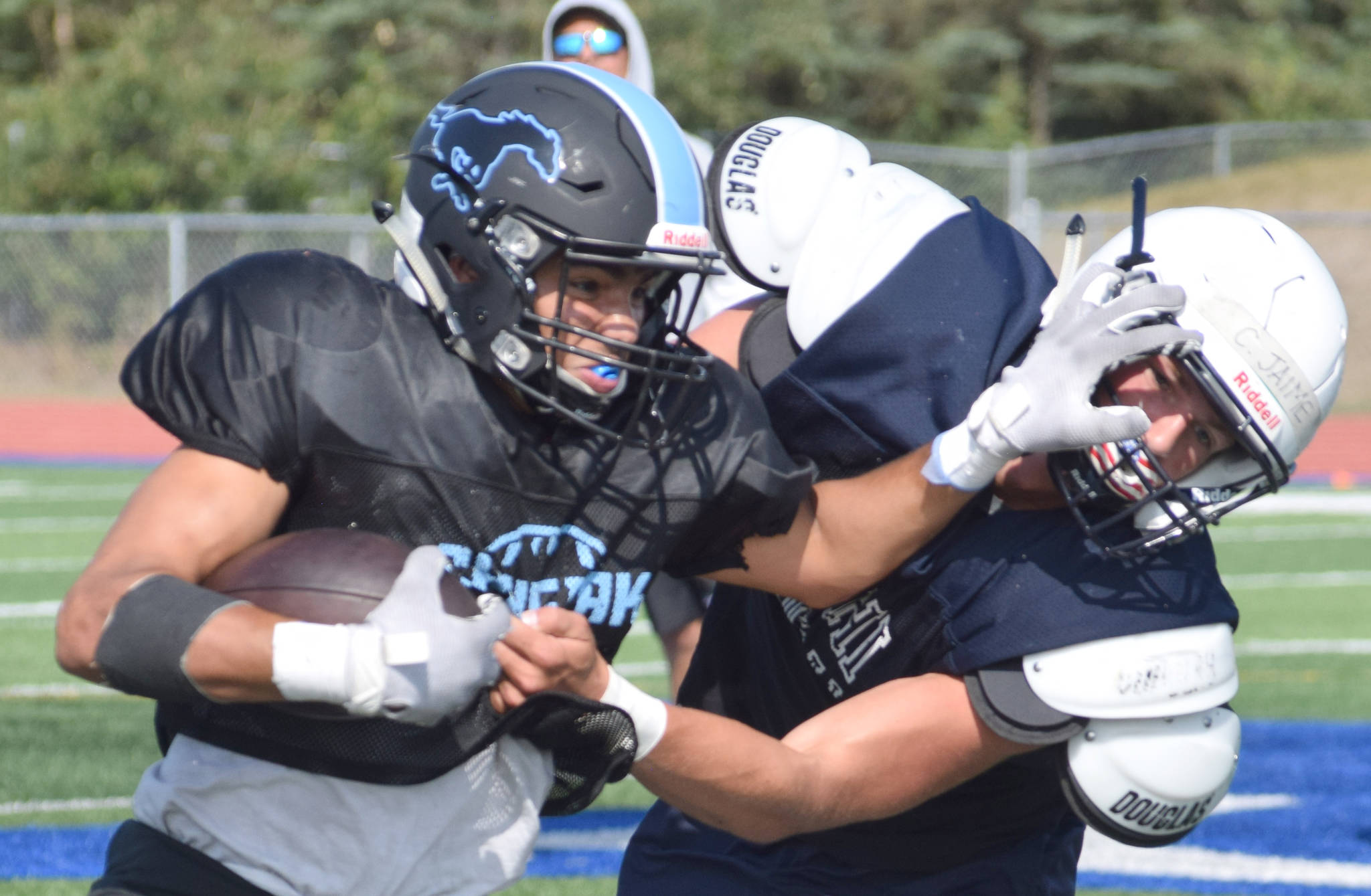 Photo by Jeff Helminiak/Peninsula Clarion                                 Chugiak’s Tyler Huffer stiff-arms Soldotna’s Hudson Metcalf during a scrimmage Saturday, Aug. 10, at Justin Maile Field in Soldotna.