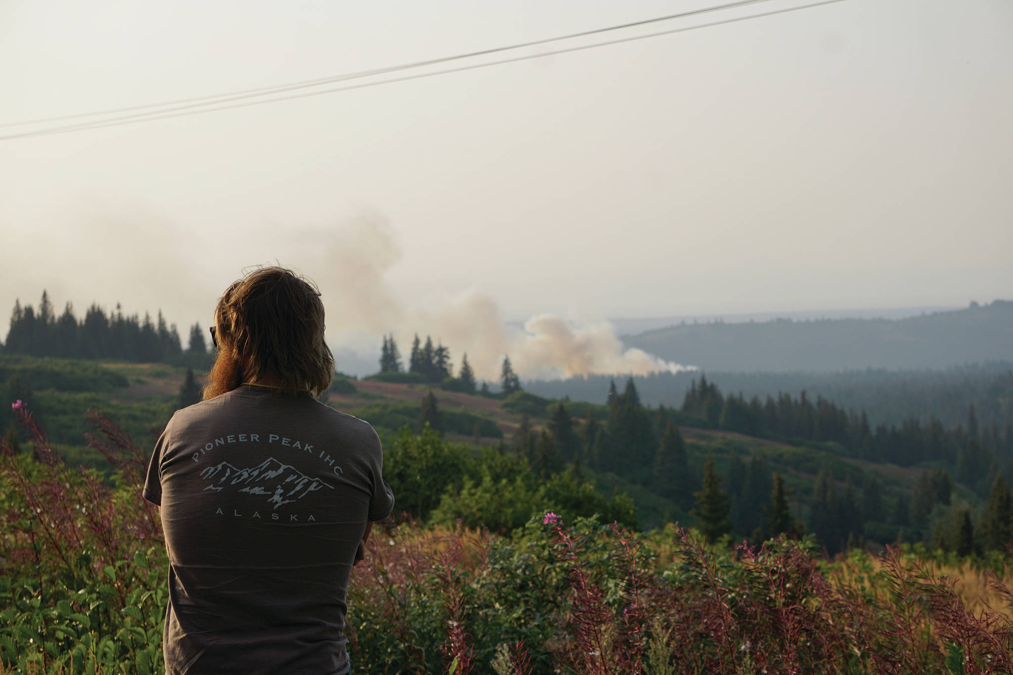 Diamond Ridge resident Parick Buongiorne watches the North Fork fire as it burns near the south end of the North Fork Road on Sunday evening, Aug. 18, 2019, near Homer, Alaska, as seen from Diamond Ridge Road. Buongiorne had previously worked as a wildlife firefighter with the Pioneer Peak crew. (Photo by Michael Armstrong/Homer News)