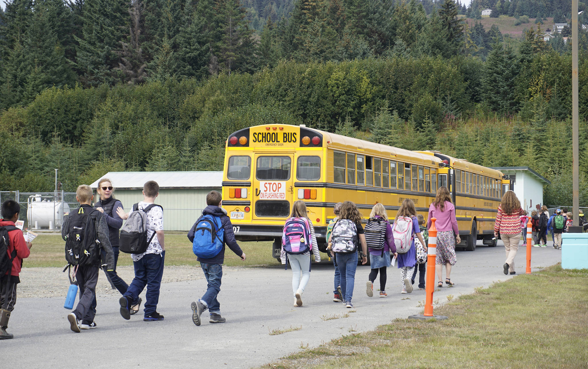 Fireweed Academy and West Homer Elementary School students and teachers walk to school buses on the first day of school on Tuesday, Aug. 20, 2019, in Homer, Alaska. A new traffic system has children lining up and boarding buses at the back of the school by the multipurpose room. (Photo by Michael Armstrong/Homer News)