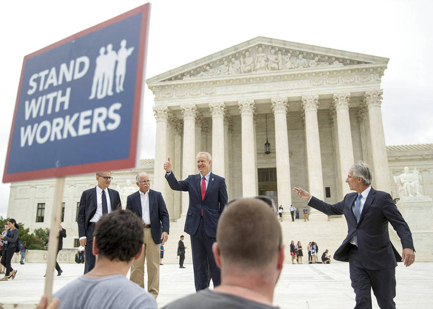 AP Photo | Andrew Harnik                                 Illinois Gov. Bruce Rauner gives a thumbs up outside the Supreme Court in June 2018 in Washington. From left are, Liberty Justice Center’s Director of Litigation Jacob Huebert, plaintiff Mark Janus, Rauner, and Liberty Justice Center founder and chairman John Tillman. The Supreme Court ruled that government workers can’t be forced to contribute to labor unions that represent them in collective bargaining, dealing a serious financial blow to organized labor.