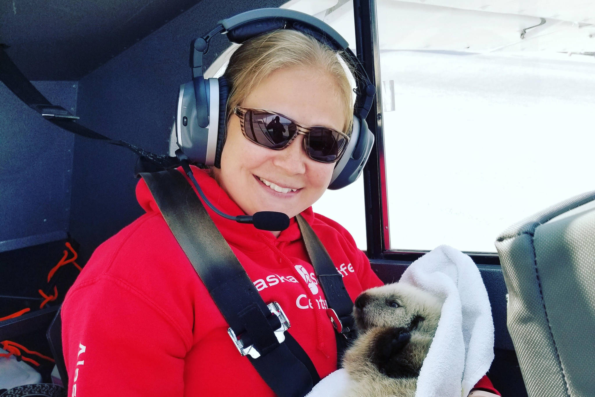 Photo courtesy Alaska SeaLife Center                                 Veterinary Technician Sarah McMillen returns with the sea otter pup in Homer, Alaska, pilot, Duke Marolfs, plane.