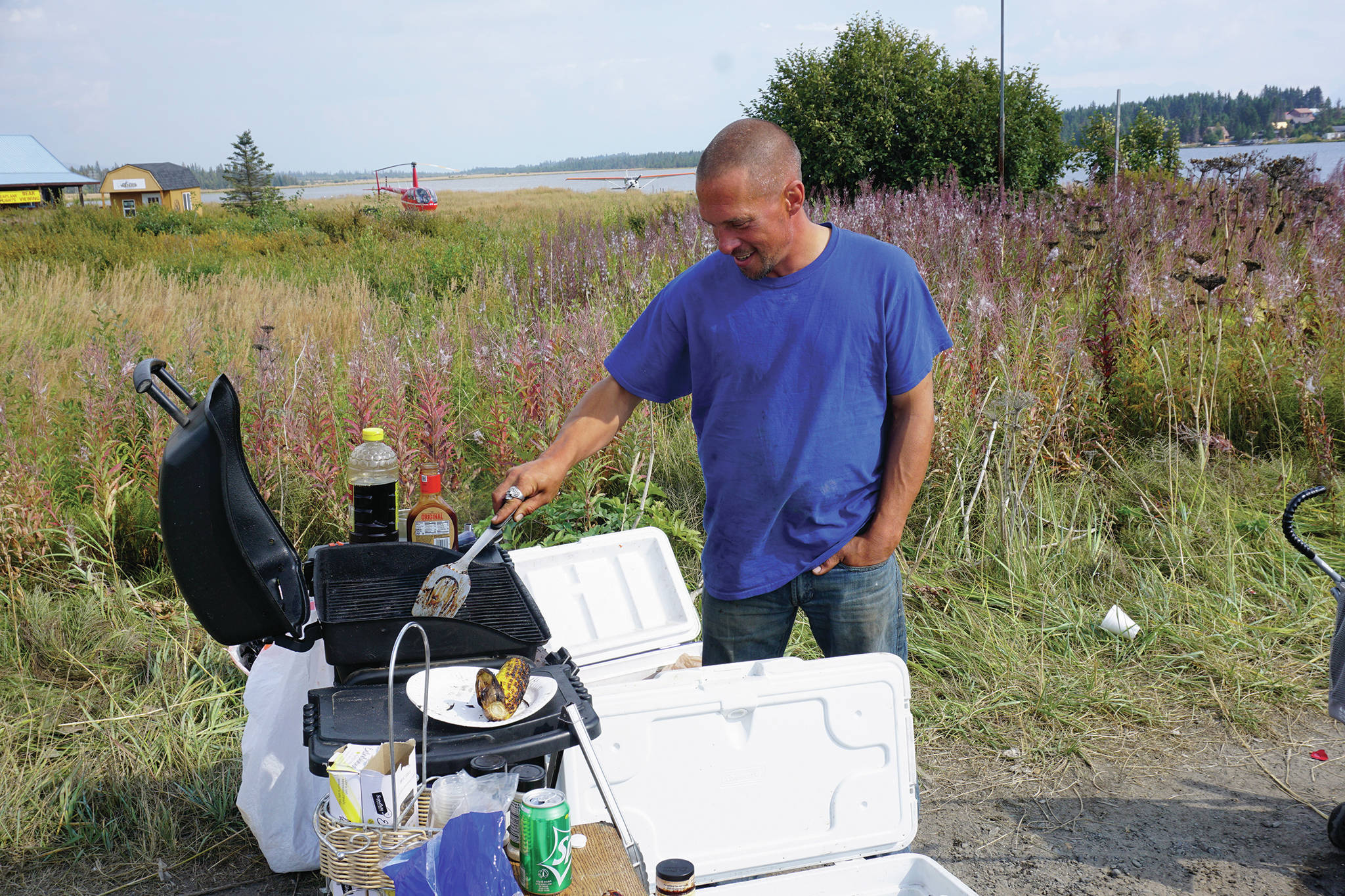 Jacob Wright works a barbecue grill by Beluga Lake on Lake Street on Monday, Aug. 26, 2019, in Homer, Alaska. Wright has been offering free food and coffee at the roadside stand and before that at Baycrest Hill. A recent arrival to Homer with his wife and two children, Wright said when he first came to Homer six weeks ago, he had mechanical troubles and then someone stole his wallet with all his gas and cards. People helped him get back on his feet, and now he’s returning the favor by offering free food. People also have given him donations of food and fish to keep his grill going. “We’re giving back to the community that helped us,” Wright said. “…This is the Alaska spirit. This is what Alaska is all about.”
