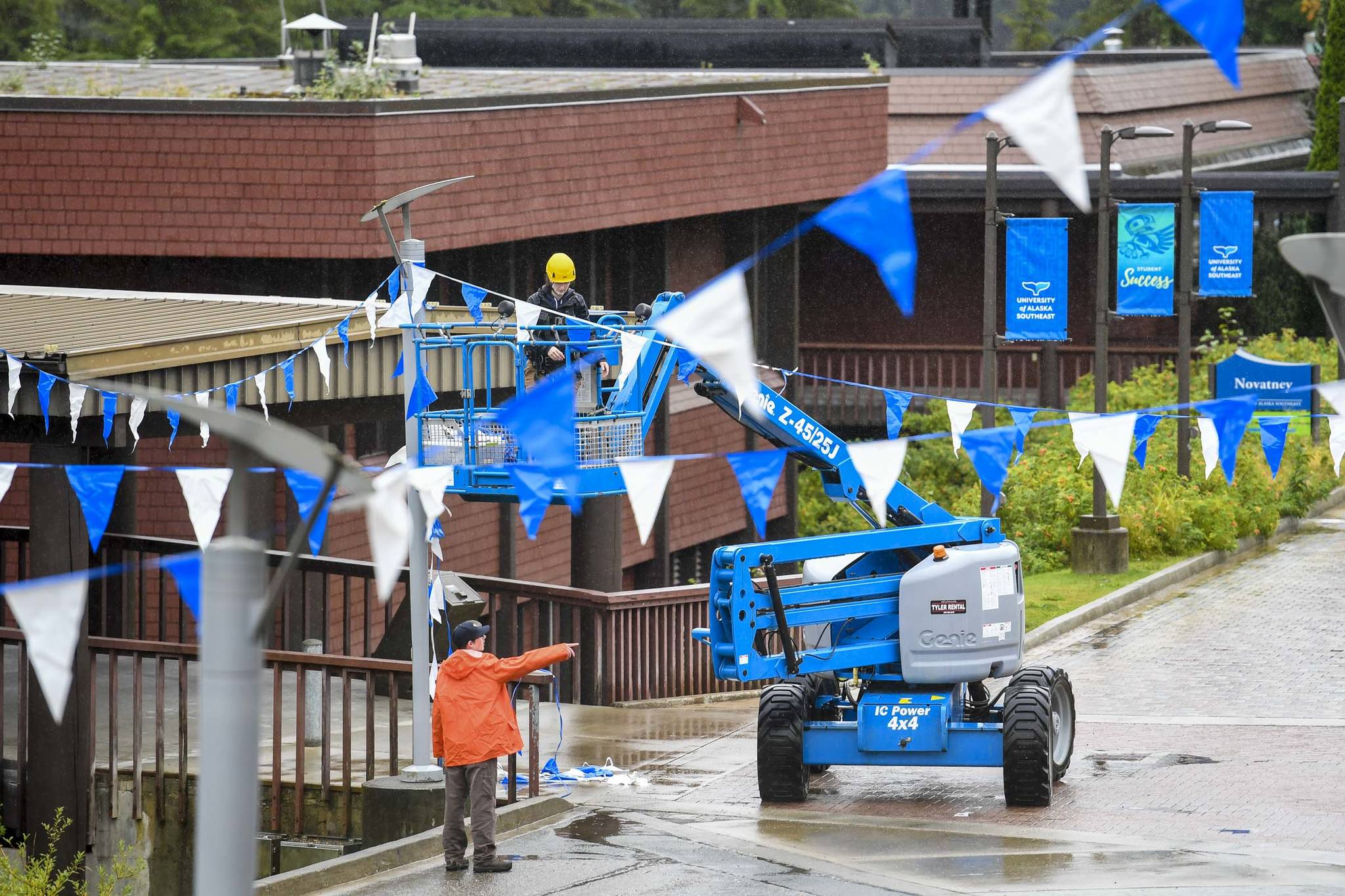 A crew hangs flags in the courtyard at the University of Alaska Southeast on Friday, Aug. 23, 2019. Classes started Monday, Aug. 26. (Michael Penn | Juneau Empire)