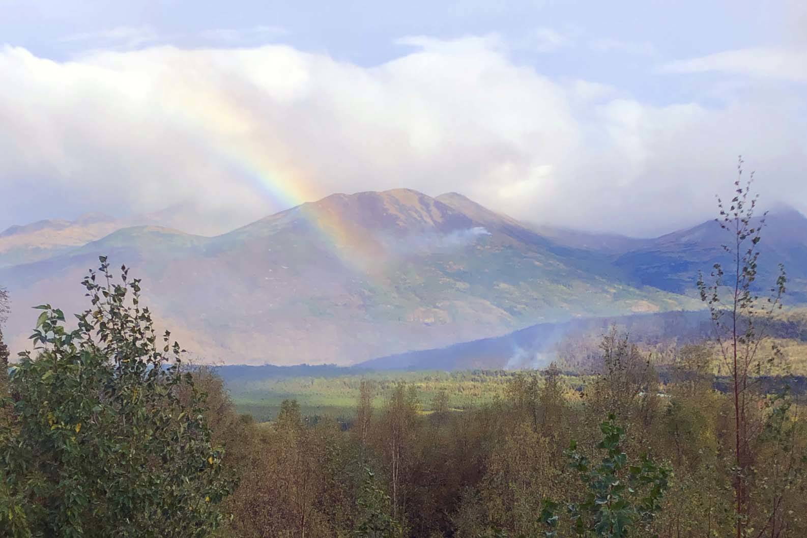 A rainbow can be seen next to rising smoke from the Swan Lake Fire in this photo released Thursday, Sept. 5. (Courtesy Kenai Peninsula Borough Office of Emergency Management)