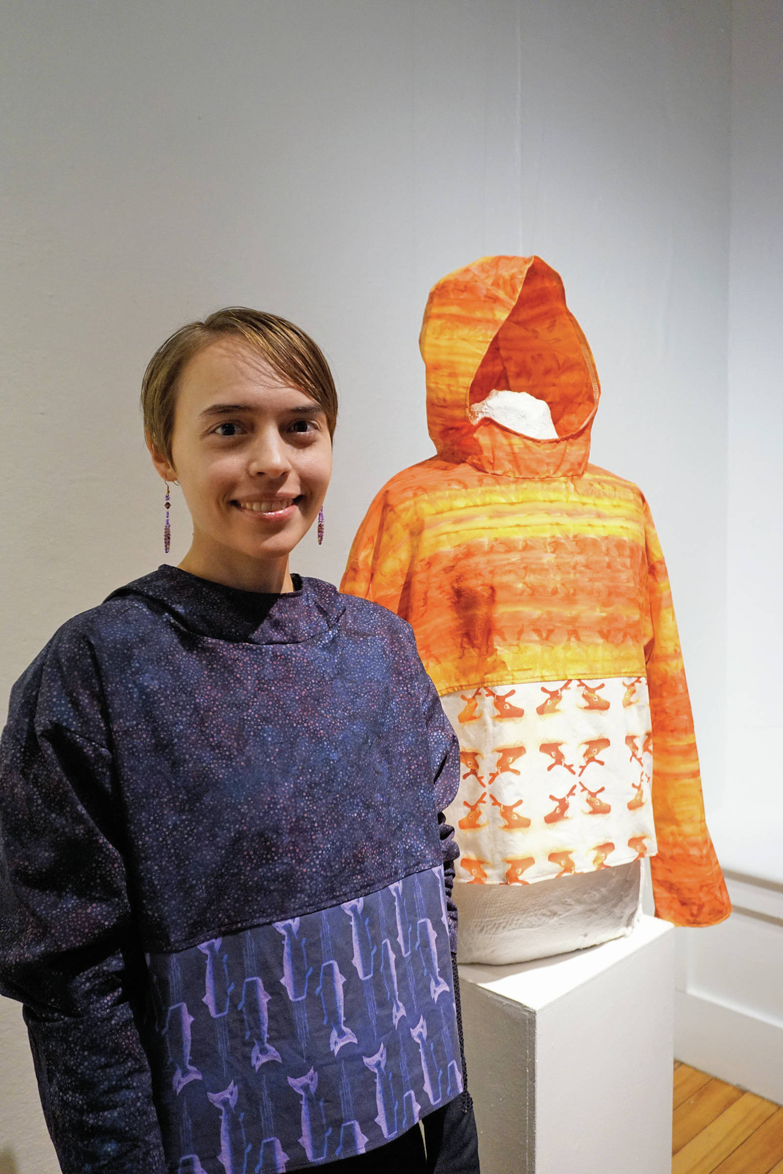 Erin Gingrich stands by her kuspuk at the opening of the “Kuspuk/Qaspeq/Atikluk” show on Oct. 5, 2019, at Bunnell Street Arts Center in Homer, Alaska. Her work includes printed fabric using designs from her sculptures. (Photo by Michael Armstrong/Homer News)