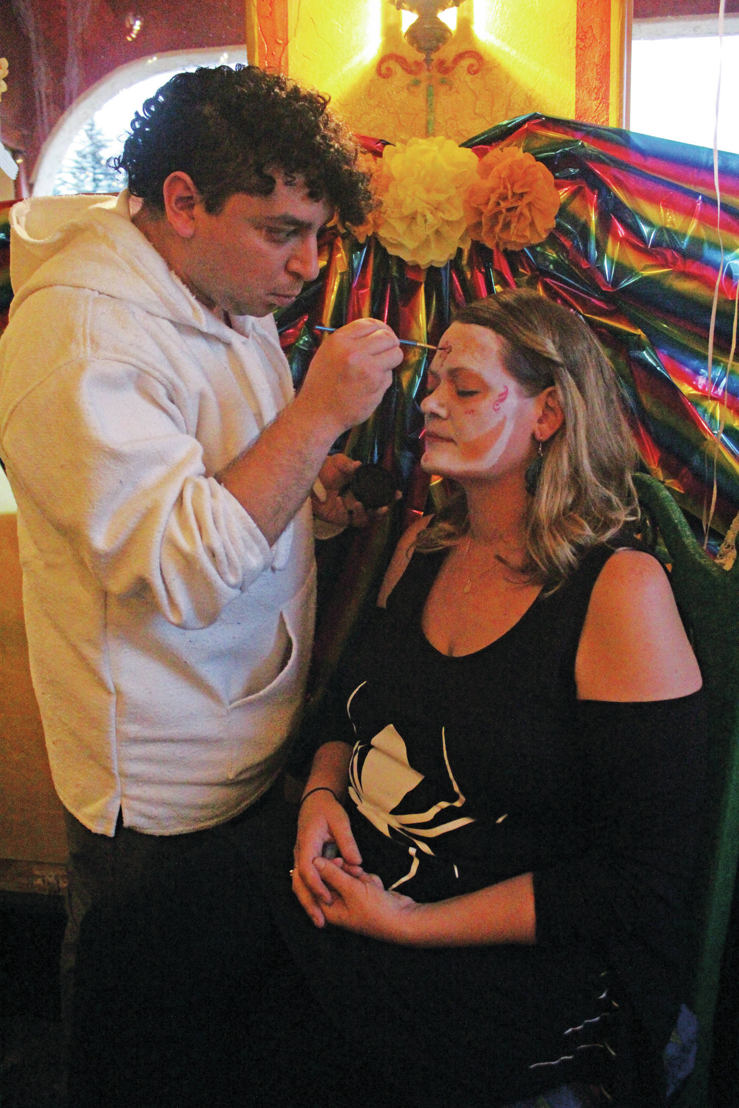 Katie Ochoa has her face painted by Isidro Sandoval during a Dia de los Muertos celebration Saturday, Nov. 2, 2019 at Don Jose’s Mexican Restaurant in Homer, Alaska. (Photo by Megan Pacer/Homer News)