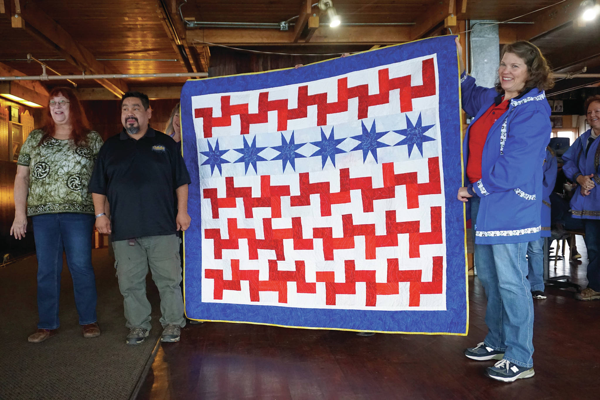 Iraq War veteran Robert “R.J.” Carlough stands with a Quilt of Valor presented to him at the Veterans Day lunch held at the Elks Lodge on Nov. 11, 2019, in Homer, Alaska. Carlough served in the U.S. Army First Division, 16th Infantry — the Big Red One — from 2002-10, and in Iraq from 2003-04. To his right is Karrie Youngblood, who quilted the work. (Photo by Michael Armstrong/Homer News)