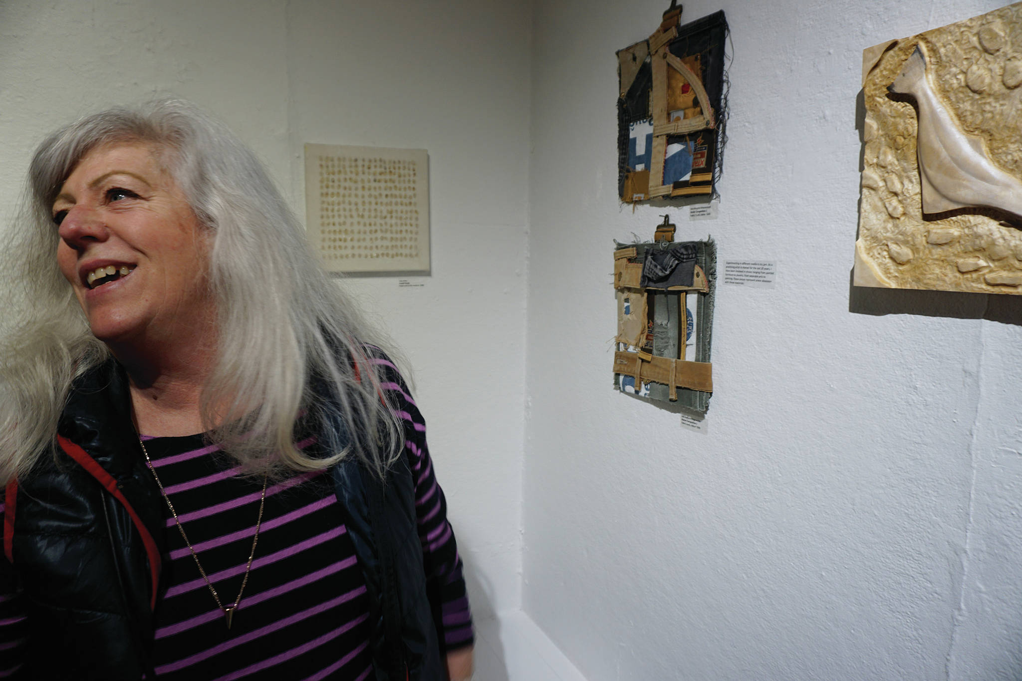 Ann-Margret Wimmerstedt stands by two of her works in the 10x10 show at Bunnell Street Arts Center that opened on Nov. 8, 2019, in Homer, Alaska. (Photo by Michael Armstrong/Homer News)