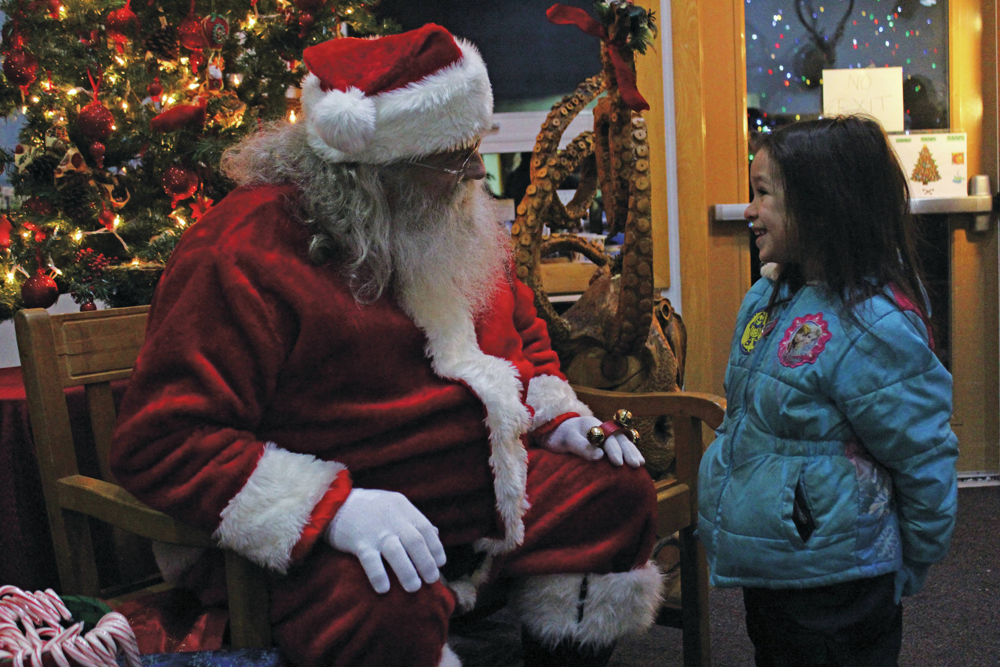 Emma Rader, 6, talks to Santa Claus before getting her photo taken with him at the annual Holiday Tree Lighting event put on by the Homer Chamber of Commerce and Visitor Center on Thursday, Dec. 5, 2019 at the chamber in Homer, Alaska. (Photo by Megan Pacer/Homer News)
