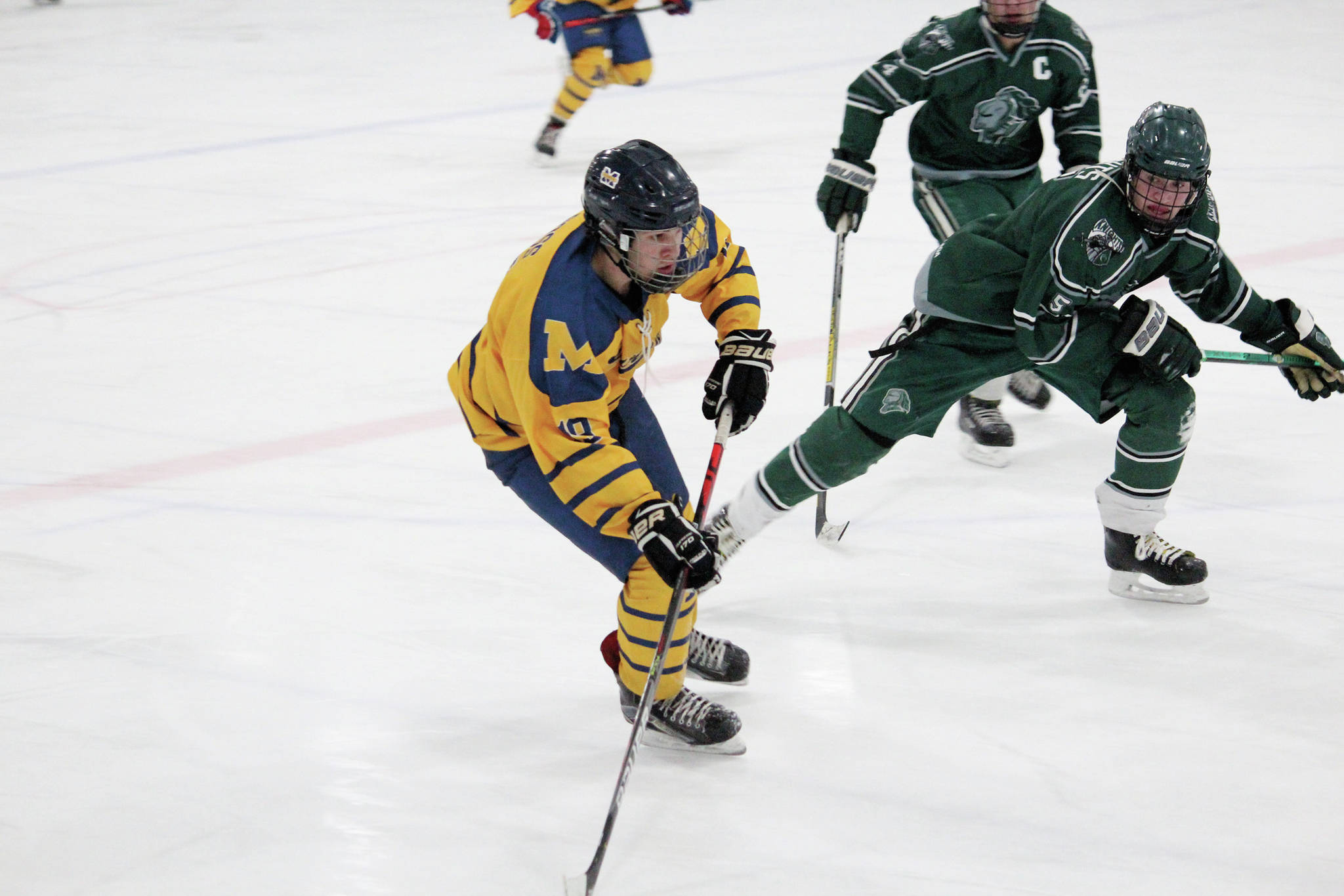 Homer’s Alden Ross takes the puck down the ice under pressure from Colony High School’s Kaden Ketchum during a Friday, Jan. 10, 2020 hockey game at Kevin Bell Arena in Homer, Alaska. (Photo by Megan Pacer/Homer News)