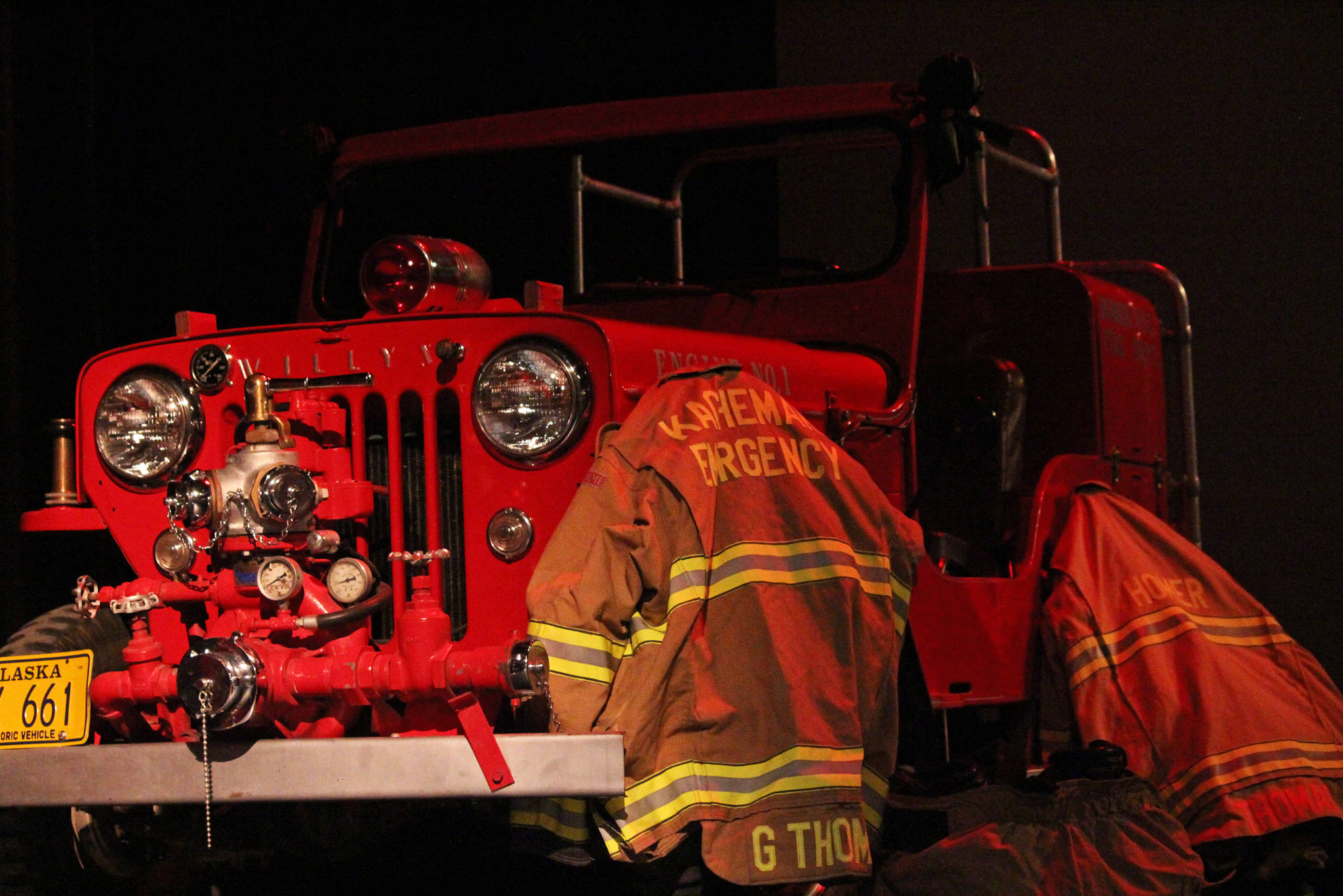 The firefighter uniforms for Gary Thomas, a former volunteer firefighter who was killed in a water heater explosion this month, hang on an antique fire truck in the Homer Mariner Theatre during a memorial for Thomas on Sunday, Jan. 19, 2020 at Homer High School in Homer, Alaska. (Photo by Megan Pacer/Homer News)