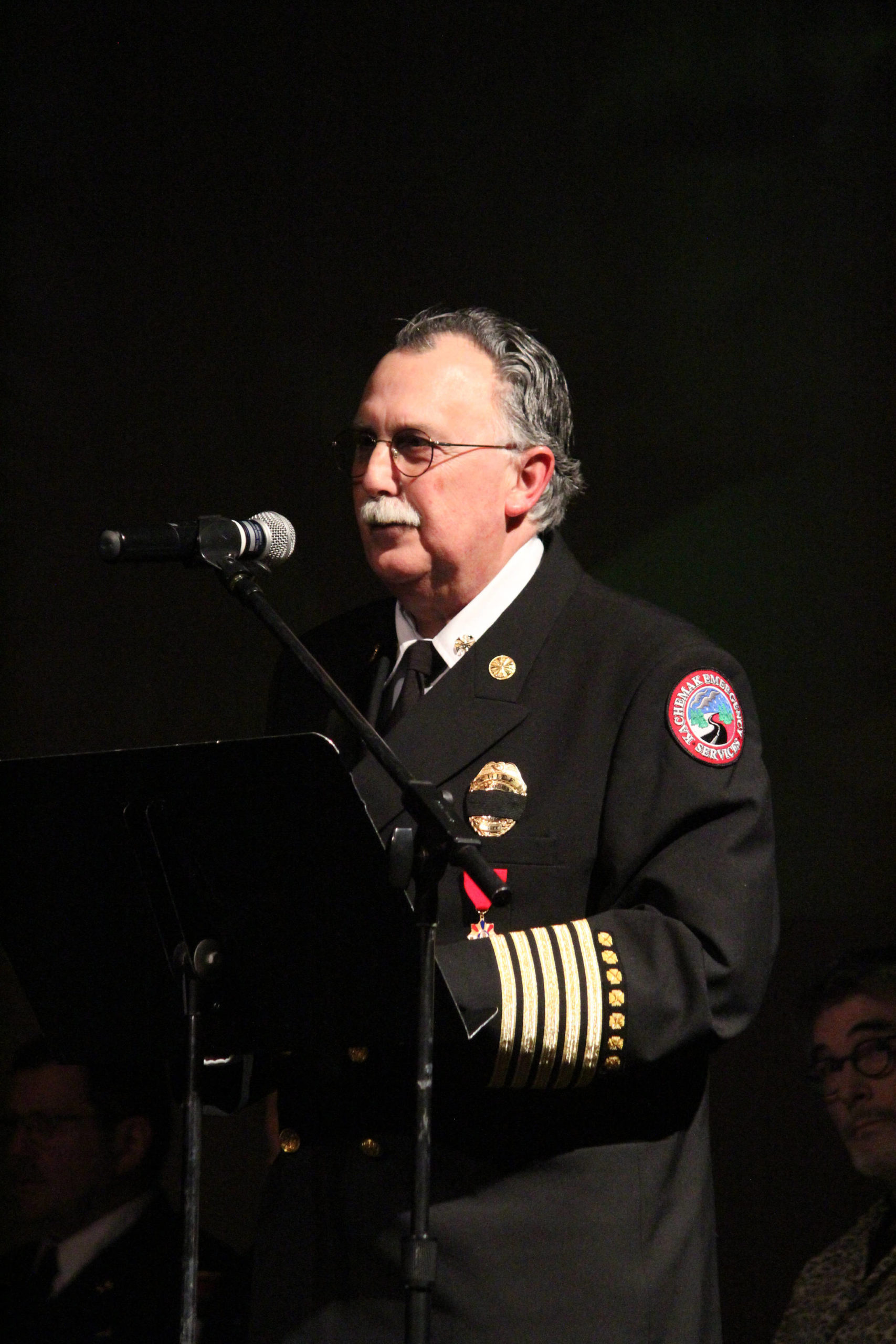 Kachemak Emergency Services Chief Bob Cicciarella speaks during a Sunday, Jan. 19, 2020 memorial for Gary Thomas, a Homer man who was killed in a water heater explosion, held at the Homer Mariner Theatre at Homer High School in Homer, Alaska. Thomas was a volunteer firefighter for both Kachemak Emergency Services and Homer Volunteer Fire Department. (Photo by Megan Pacer/Homer News)