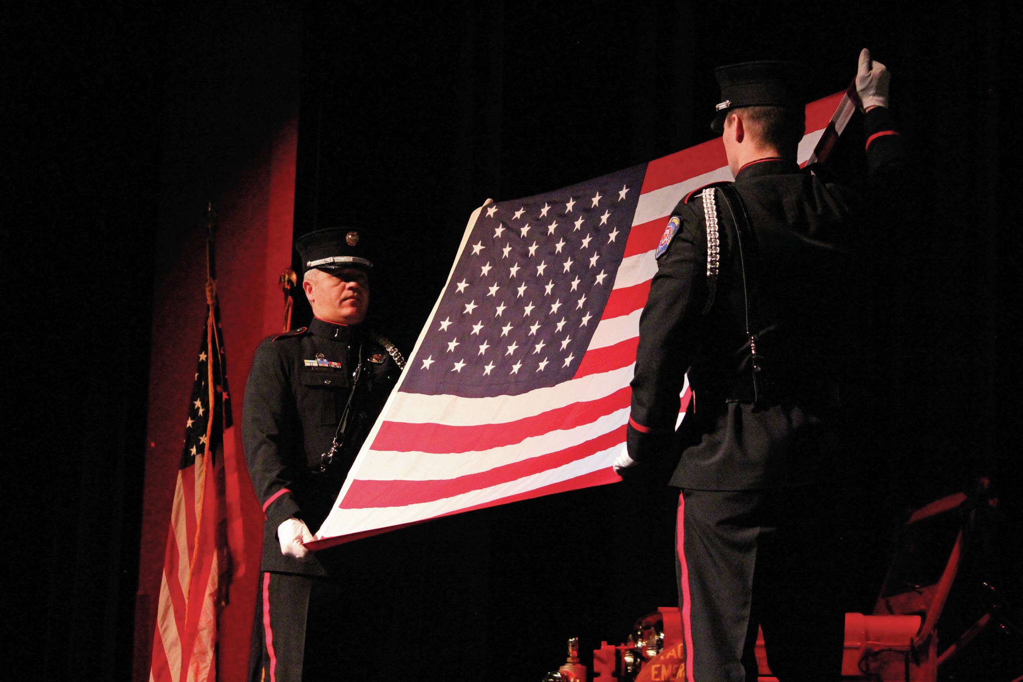 An American flag is presented in a ceremony before being given to the family of Gary Thomas during a memorial held for him Sunday, Jan. 19, 2020 at the Homer Mariner Theatre at Homer High School in Homer, Alaska. Thomas, who died this month in a water heater explosion, was a volunteer firefighter for more than 40 years. (Photo by Megan Pacer/Homer News)