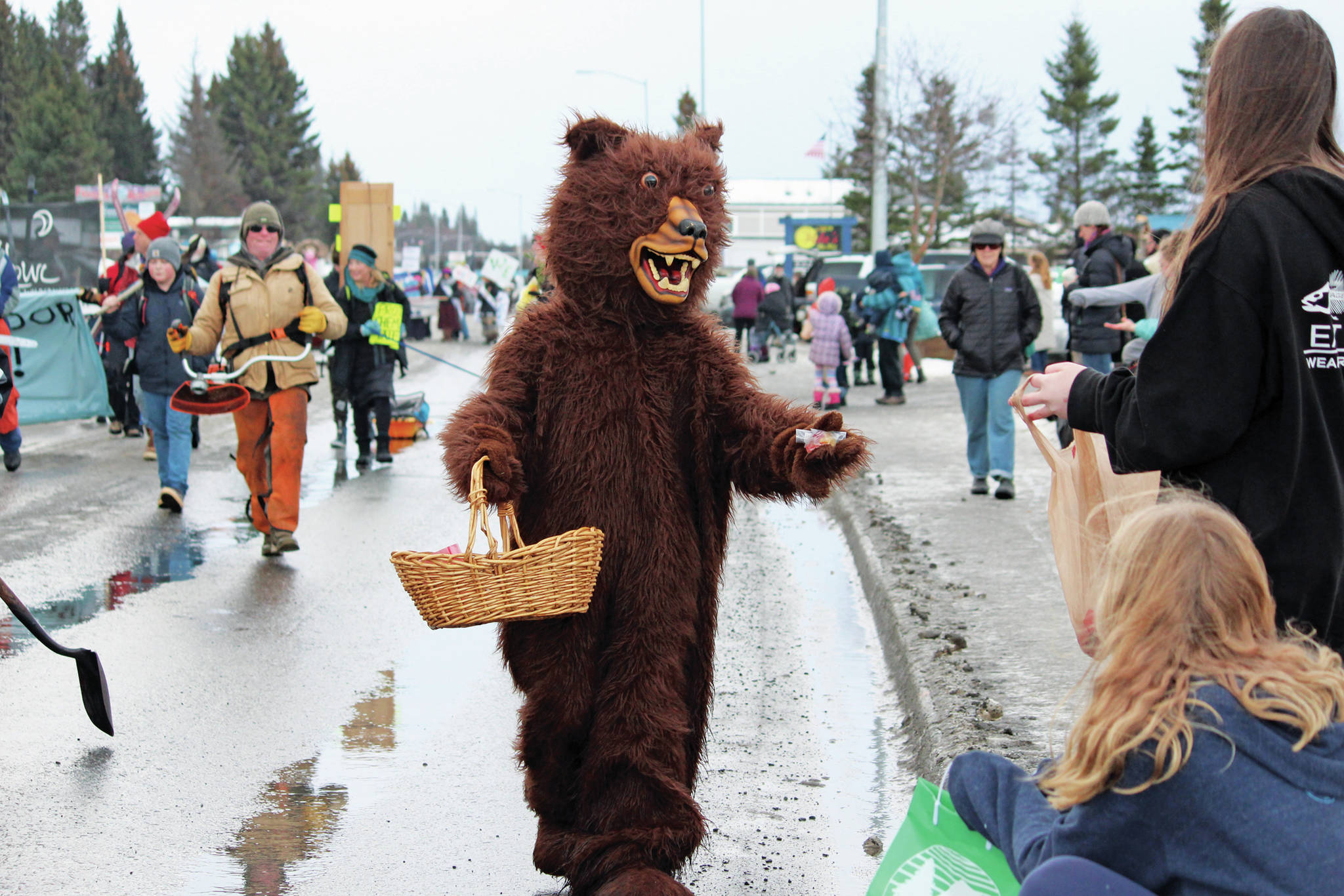 A parade marcher in a bear costume hands out goodies to families attending this year’s Homer Winter Carnival on Saturday, Feb. 8, 2020 on Pioneer Avenue in Homer, Alaska. (Photo by Megan Pacer/Homer News)