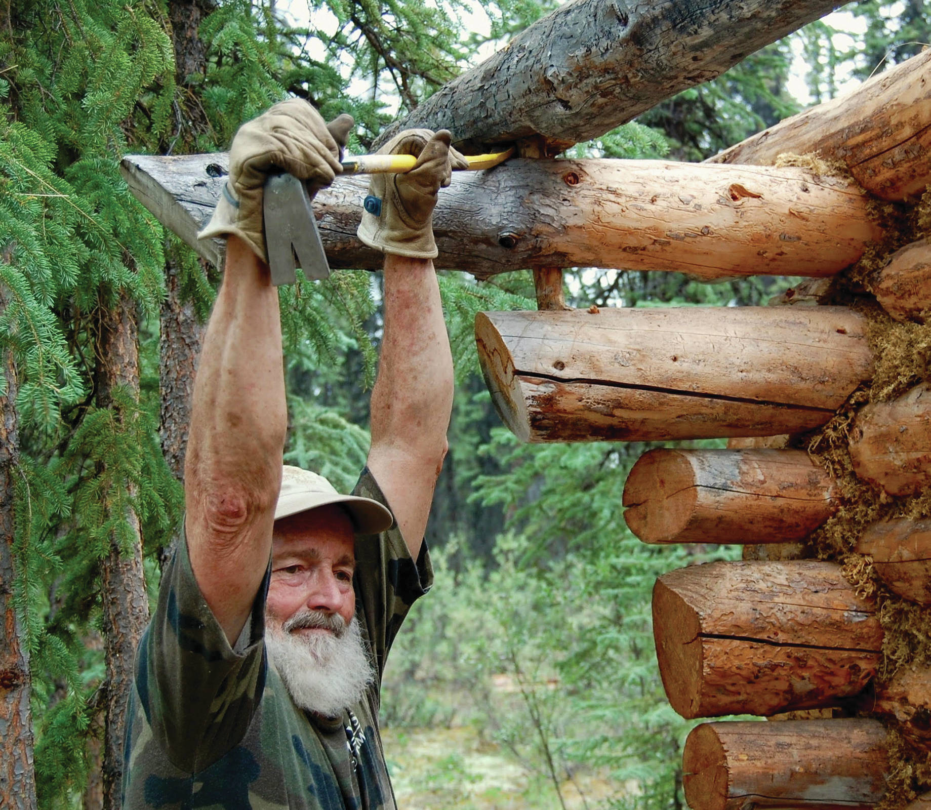 Tom Irons works on taking apart the cabin he and Jean Aspen built in a still photo from the movie “ReWilding Kernwood,” filmed from 2016 to 2018 on the Chandalar River in the Brooks Range, Alaska. (Photo courtesy of Jean Aspen)