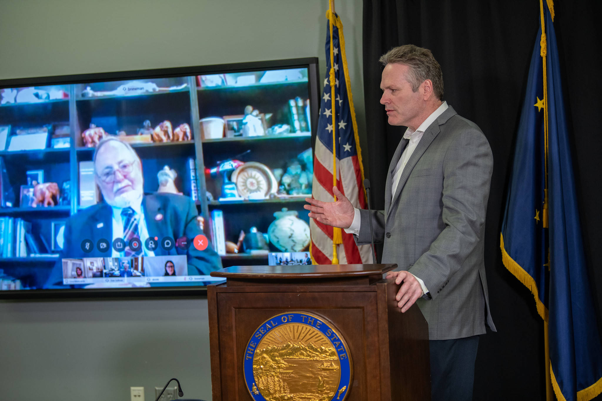 Gov. Mike Dunleavy speaks while Rep. Don Young, R-Alaska, looks on via a video feed at a press conference on March 30, 2020 in the Atwood Building in Anchorage, Alaska. (Photo courtesy Office of the Governor)