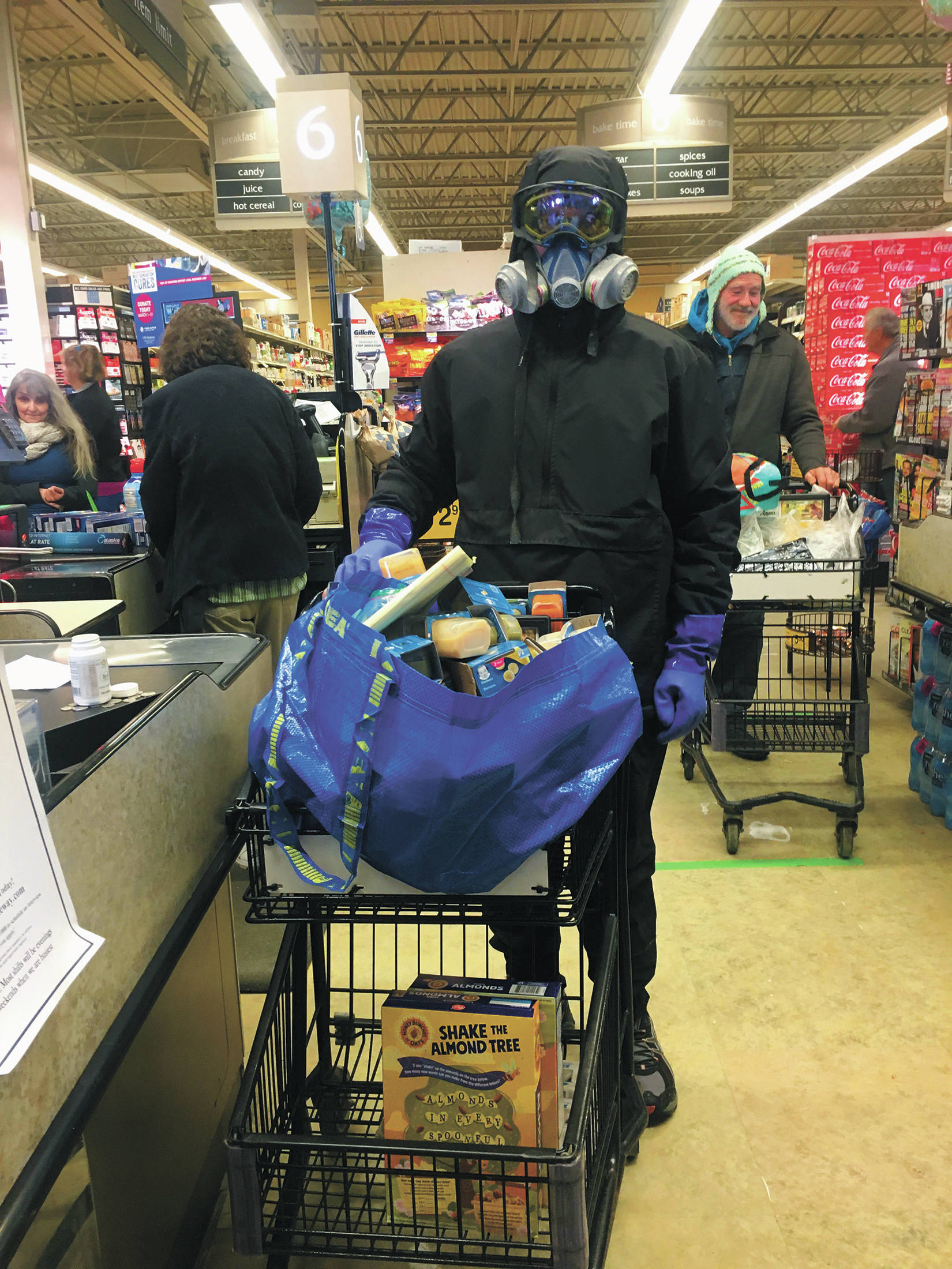 Bjørn Olson shops in protective gear for people who can’t go to the store themselves on March 23, 2020 at Safeway in Homer, Alaska. Olson volunteers each Monday to shop for the elderly, those at increased risk of contracting the novel coronavirus or those self isolating at home due to the spread of the illness it causes, COVID-19. (Photo by Megan Pacer/Homer News)