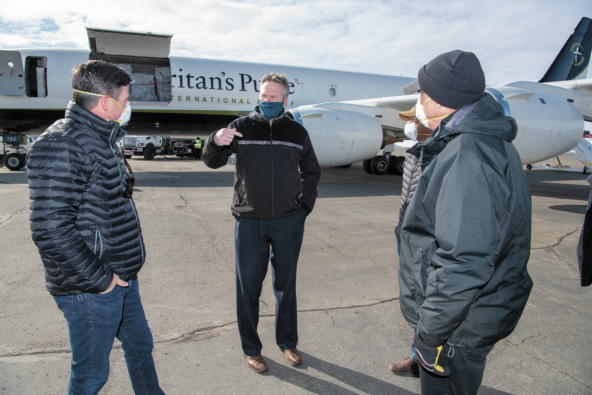 Gov. Mike Dunleavy (center) speaks with Edward Graham (left) of Samaritan’s Purse as two other Samaritan’s Purse staff members look on, Monday, April 6, 2020 at Ted Stevens International Airport in Anchorage, Alaska. Dunleavy met the crew and staff of the Samaritan’s Purse DC-8 at the airport as they offloaded thousands of pounds of medical supplies bound for rural Alaska. (Photo courtesy Office of the Governor)