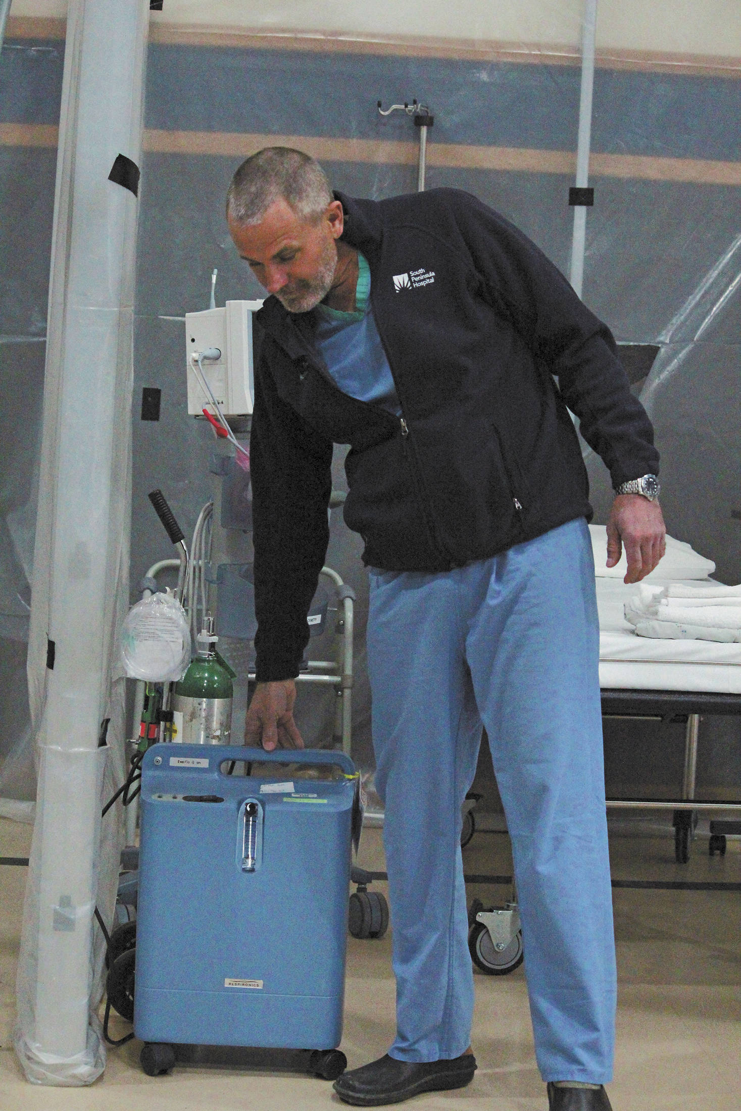 Dr. Todd Boling, medical director of the Alternate Care Site Leadership team, points out one of several needed oxygen concentrators in South Peninsula Hospital’s alternate care site for COVID-19 patients on Monday, April 6, 2020 at the site at Christian Community Church in Homer, Alaska. The oxygen concentrators will be needed on site for COVID-19 patients having trouble breathing. (Photo by Megan Pacer/Homer News)