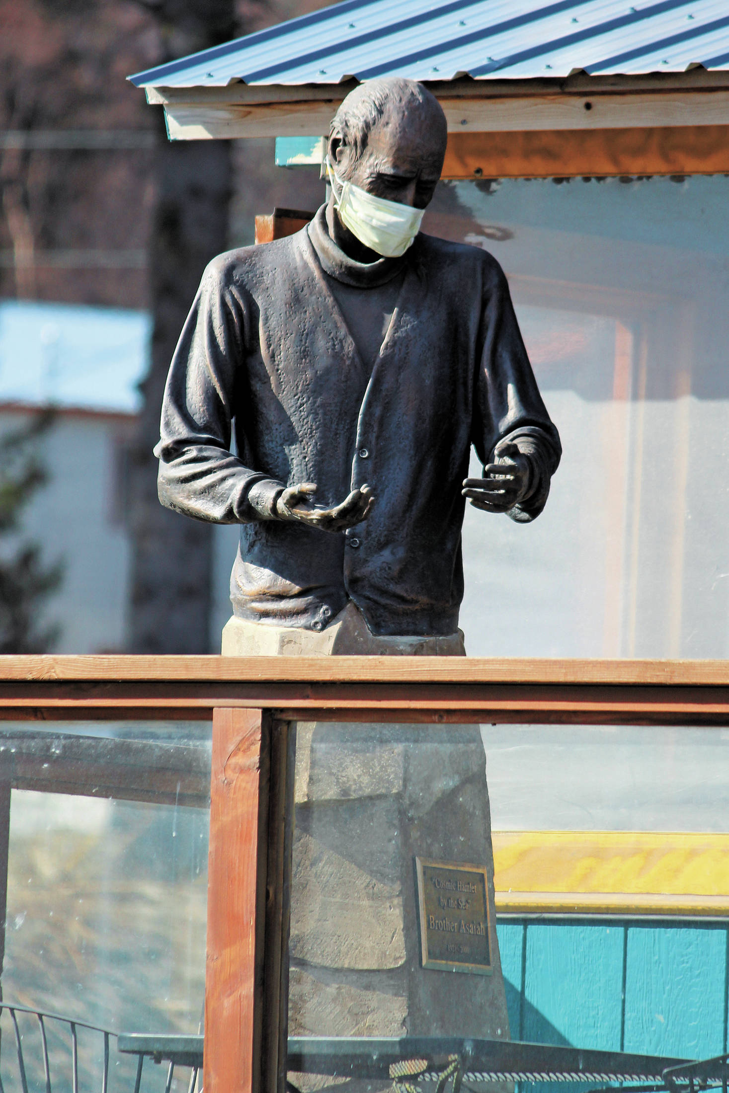 The statue of Brother Asaiah Bates that stands at Cosmic Kitchen is seen wearing a mask on Monday, April 6, 2020 in Homer, Alaska. The state of Alaska is currently advising people to wear protective cloth coverings when they have to go out in public for essentials. (Photo by Megan Pacer/Homer News)