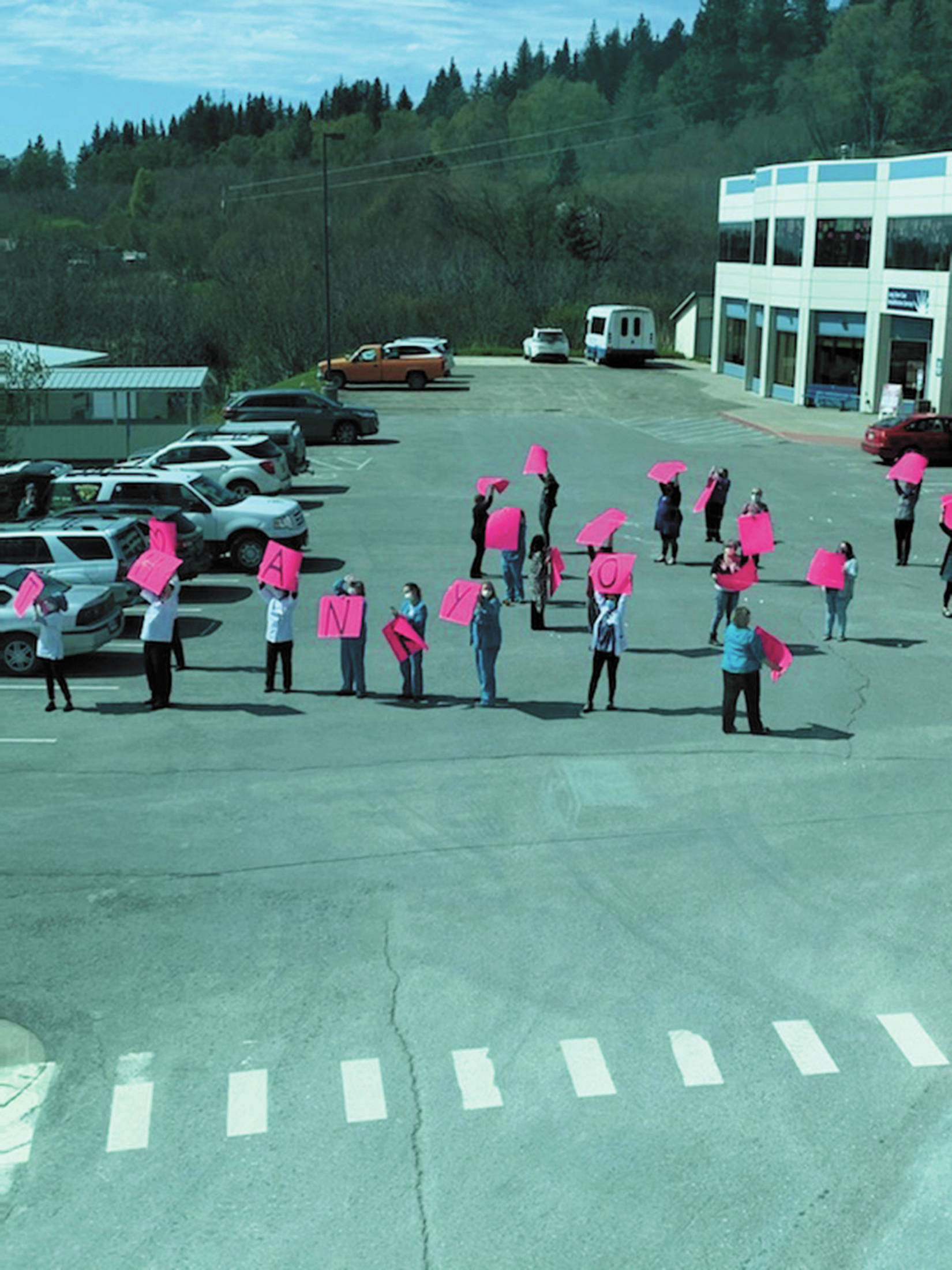 Health care workers hold up signs spelling out “thank you” while four F-22 Raptors fly over Homer at South Peninsula Hospital on Friday, May 15, 2020 in Homer, Alaska. (Photo by Lisa Talbott)