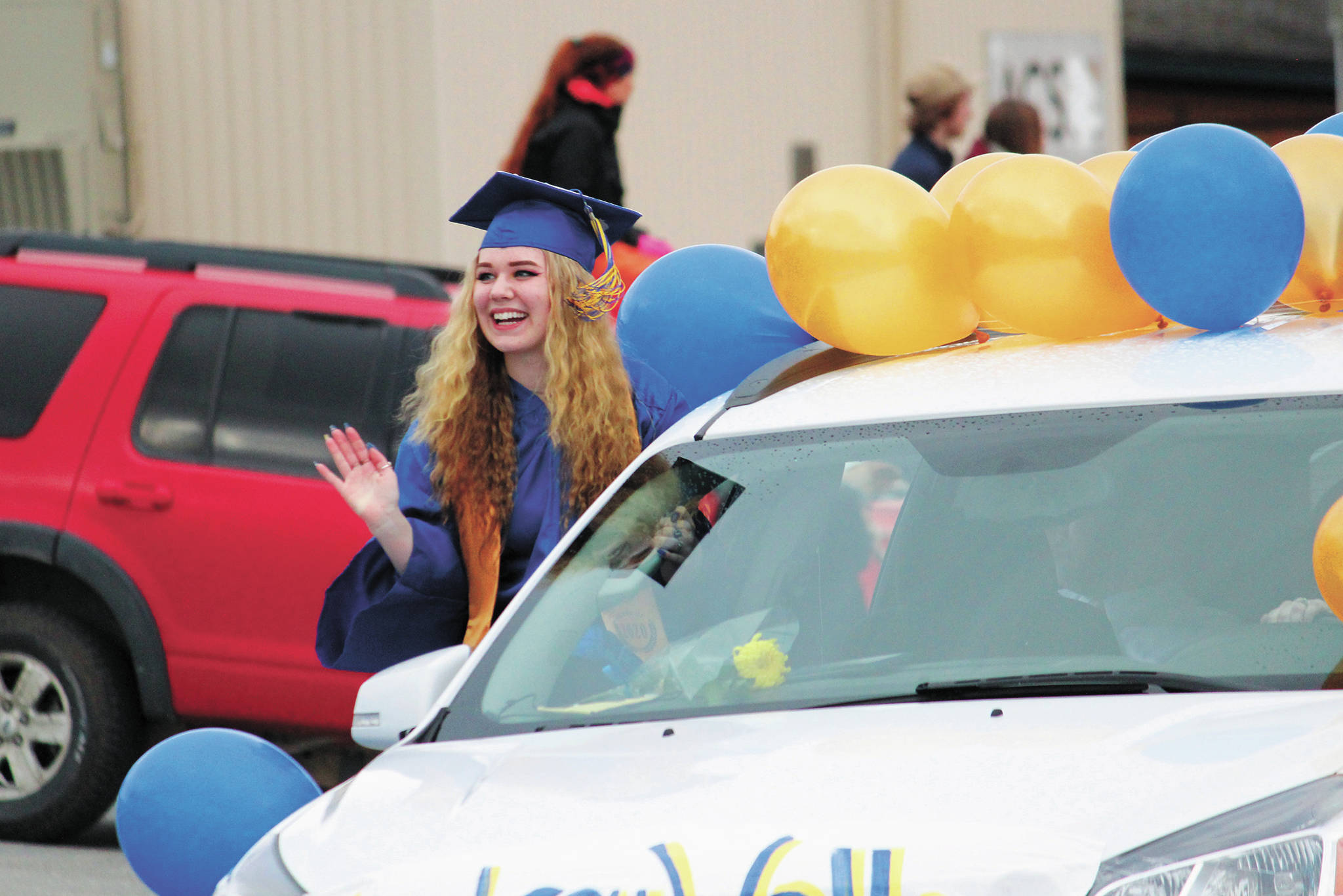 Homer High School graduate Audrey Wallace waves to onlookers while participating in a procession through town with the class of 2020 following their commencement ceremony Monday, May 18, 2020 in Homer, Alaska. (Photo by Megan Pacer/Homer News)