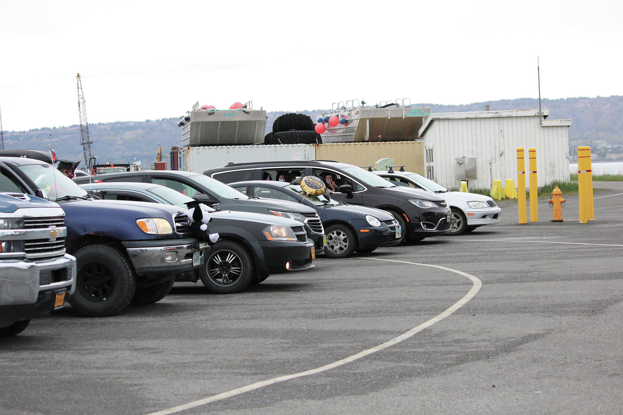 Vehicles wait in line with graduates inside them during a commencement ceremony for Homer Flex School on Monday, May 18, 2020 at the Homer Harbor in Homer, Alaska. Students got out of the vehicles to collect their diplomas and get photos before returning. The program was pre-recorded and played on public radio. (Photo by Megan Pacer/Homer News)
