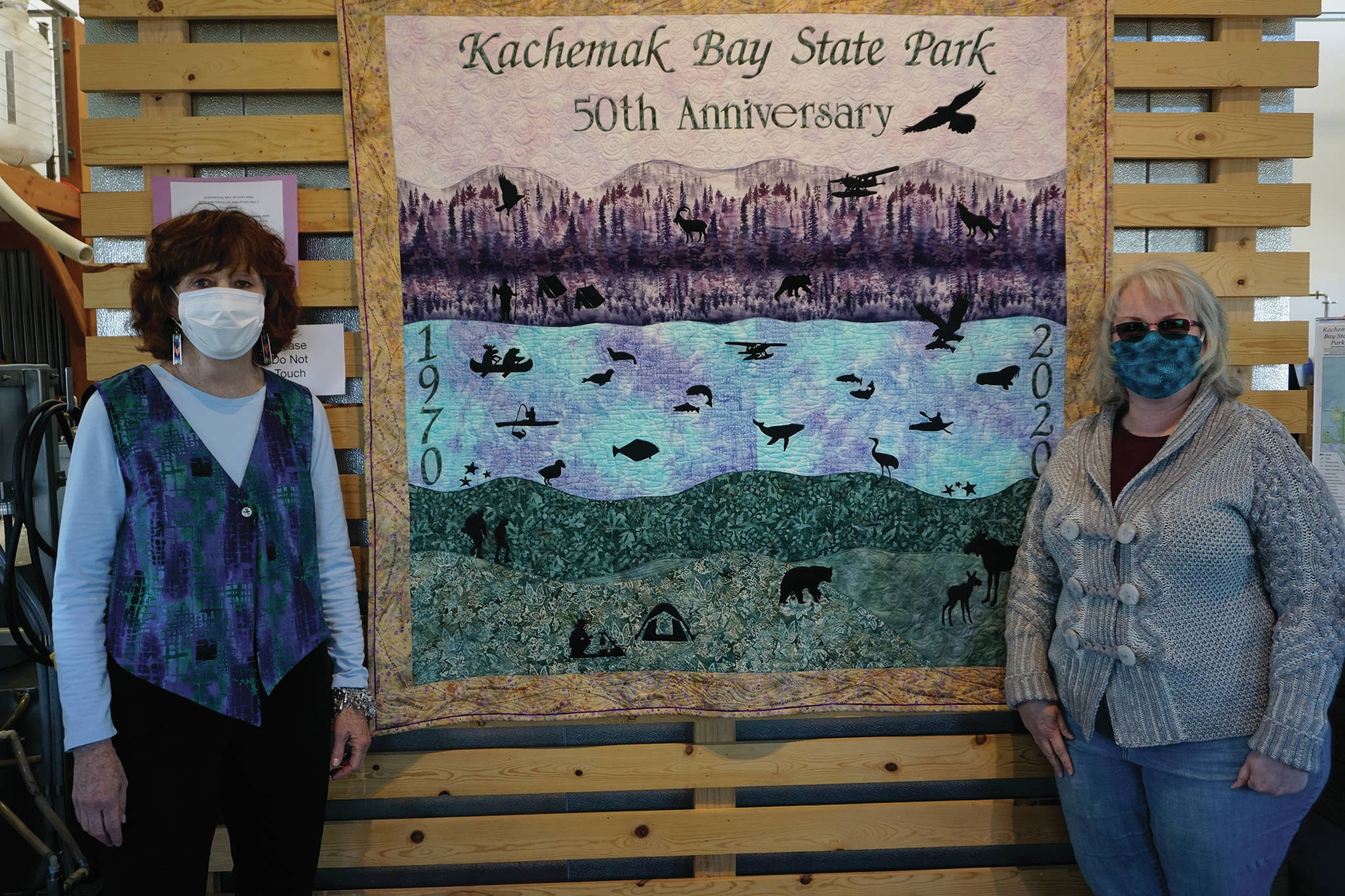 Patrice Krant, left, and Karrie Youngblood, right, pose next to their quilt commemorating the 50th anniversary of Kachemak Bay State Park on Saturday, May 16, 2020, at Grace Ridge Brewery in Homer, Alaska. Krant designed and sewed the quilt and Youngblood did the quilting. Rick Rosebbloom and Krant donated materials and funded the quilt. The back of the quilt has a map of Kachemak Bay State Park. The quilt also features text listing 50 things to do in the park. The quilt was unveiled last Saturday along with the introduction of a special Grace Ridge 50th Anniversary beer. (Photo by Michael Armstrong/Homer News)
