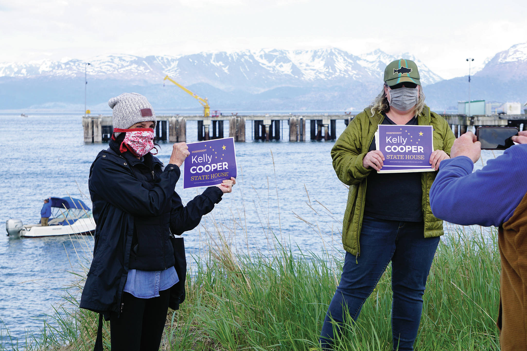 Melanie Dufour, left, and Bridget Maryott, center, pose for a photo for Dave Aplin, right, at Kelly Cooper’s “Rally on the Bay” campaign kick-off on Tuesday, May 26, 2020. Cooper spoke from the stern of the F/V Sea Nymph in Kachemak Bay near the Deep Water Dock in Homer, Alaska. About 50 people attended the rally from onshore, in fishing and pleasure boats, and in kayaks. (Photo by Michael Armstrong/Homer News)
