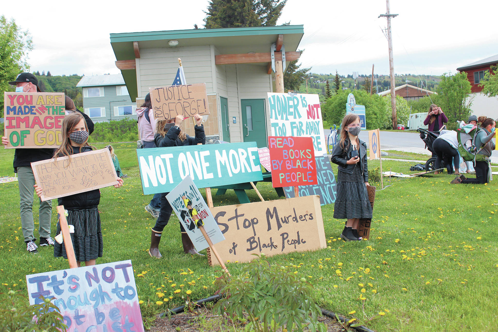 Families and their children wave to drivers from a Black Lives Matter demonstgration at WKFL Park on Tuesday, June 2, 2020 in Homer, Alaska. (Photo by Megan Pacer/Homer News)